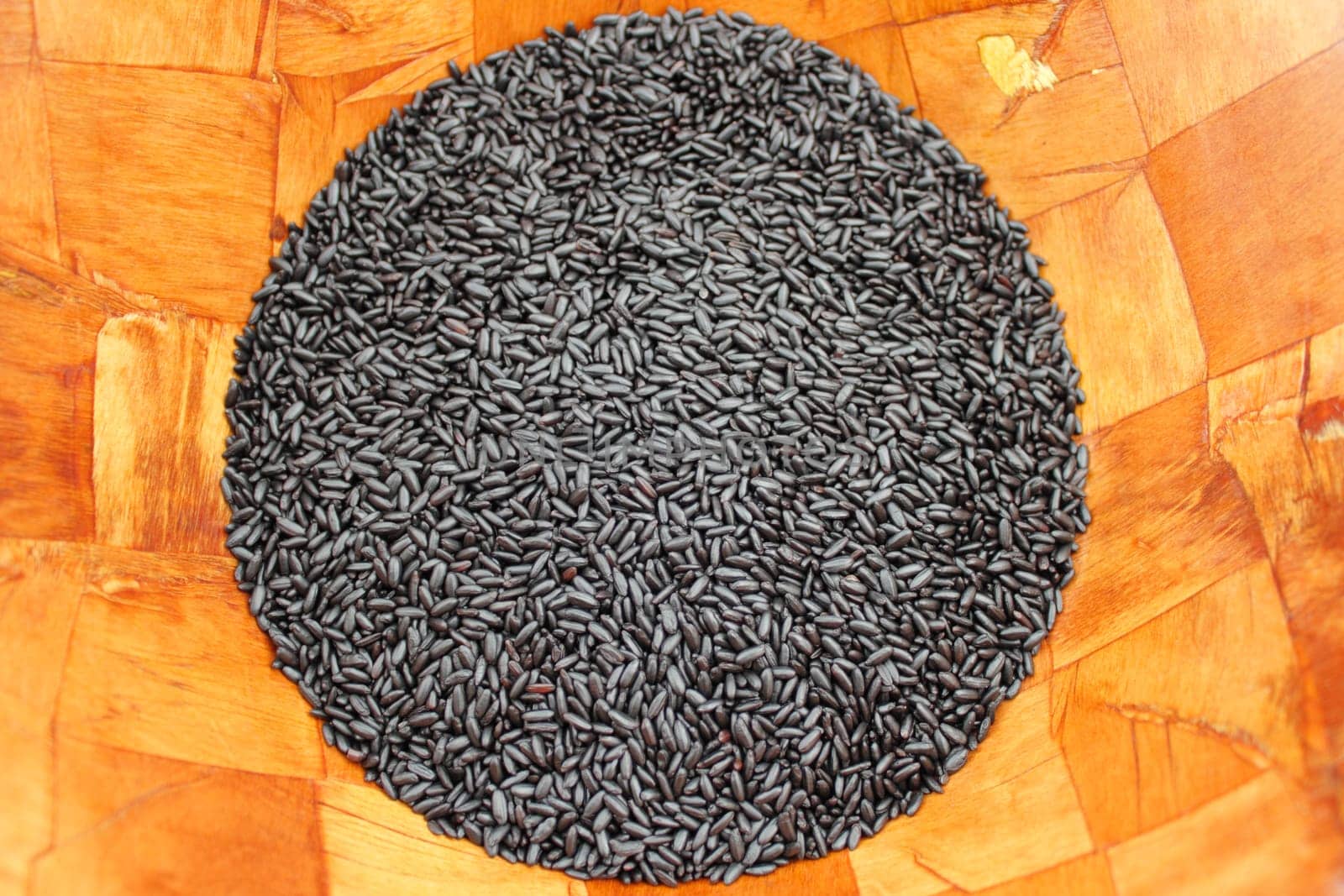 Close up of organic black purple rice in a wood bowl.