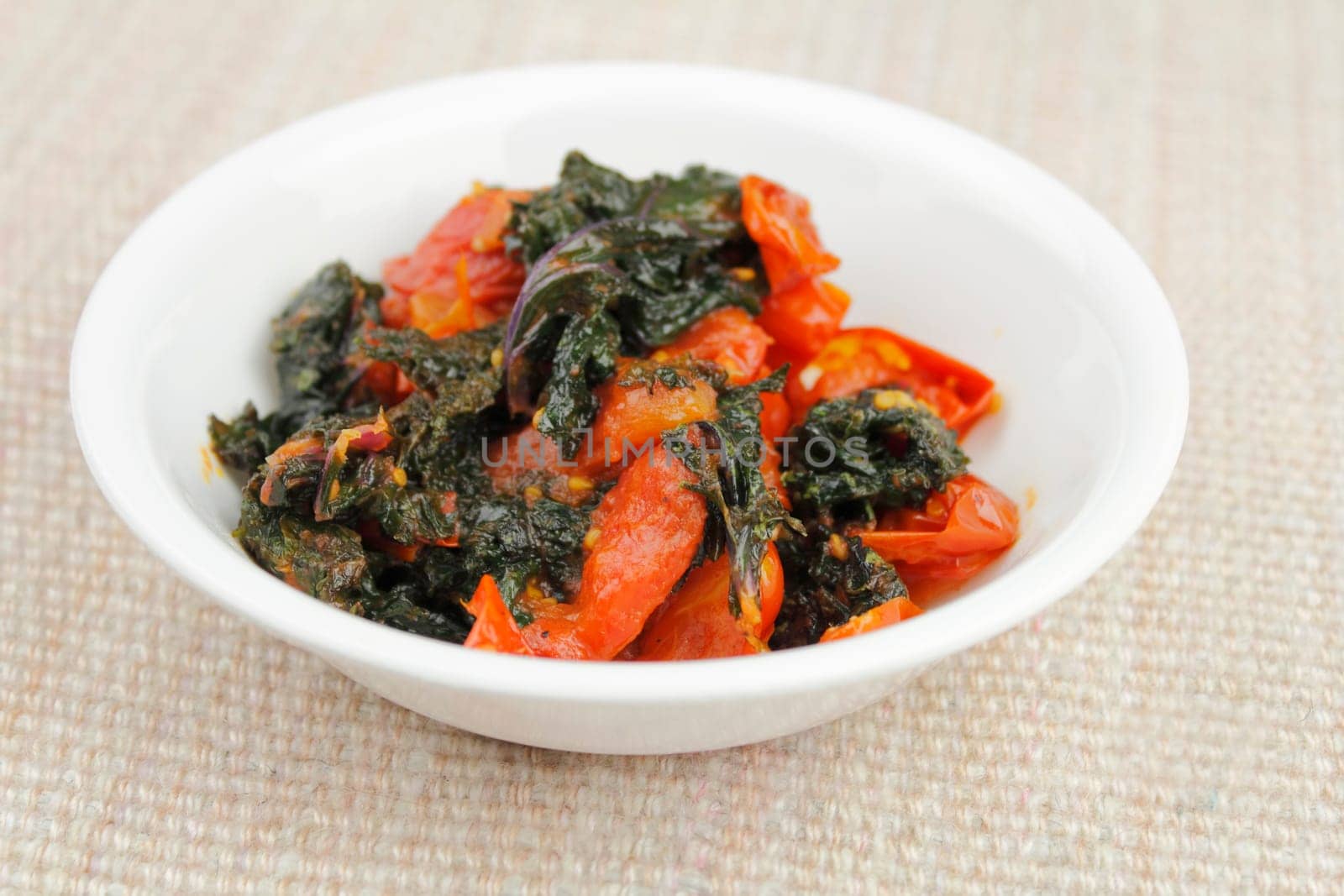 Small bowl of cooked red kale and cherry tomatoes.