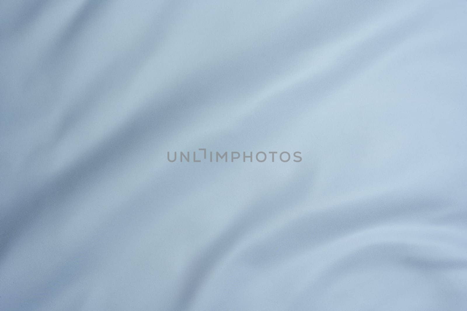 Close-up of light blue fabric with gentle folds and smooth texture, creating a minimalistic background.