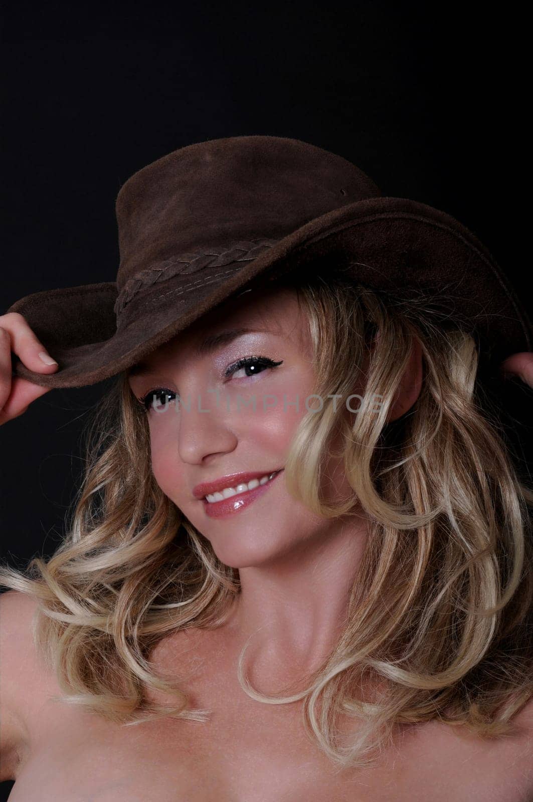 Lovely girl wearing a cowboy hat isolated over black