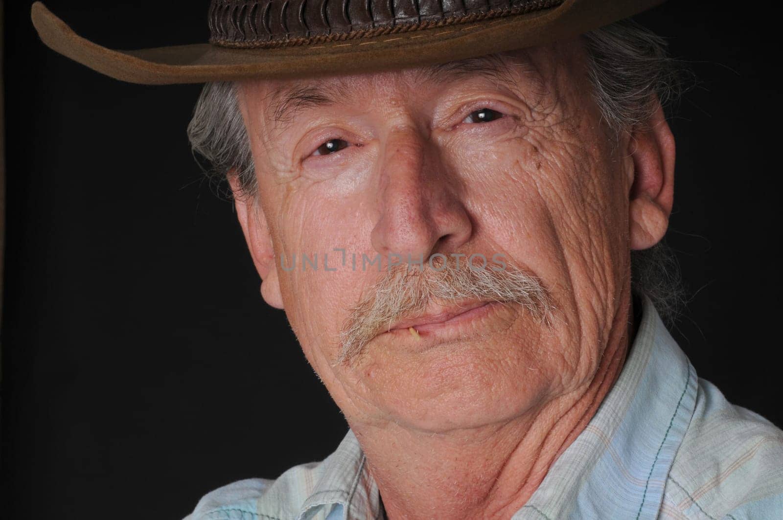 Portrait of an old cowboy with a toothpiclk in his mouth