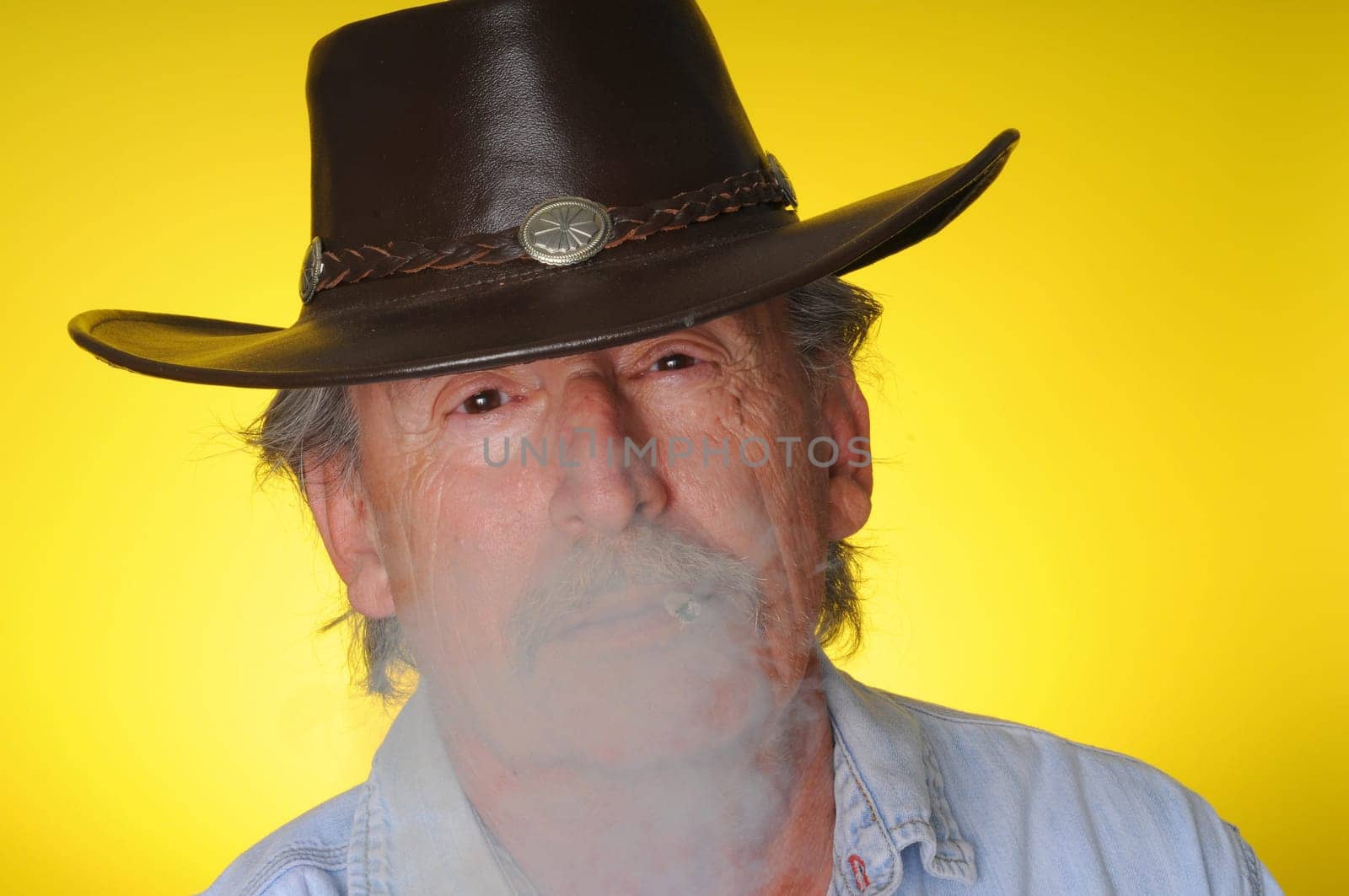 Old senior cowboy smoking a hand rolled cigarette