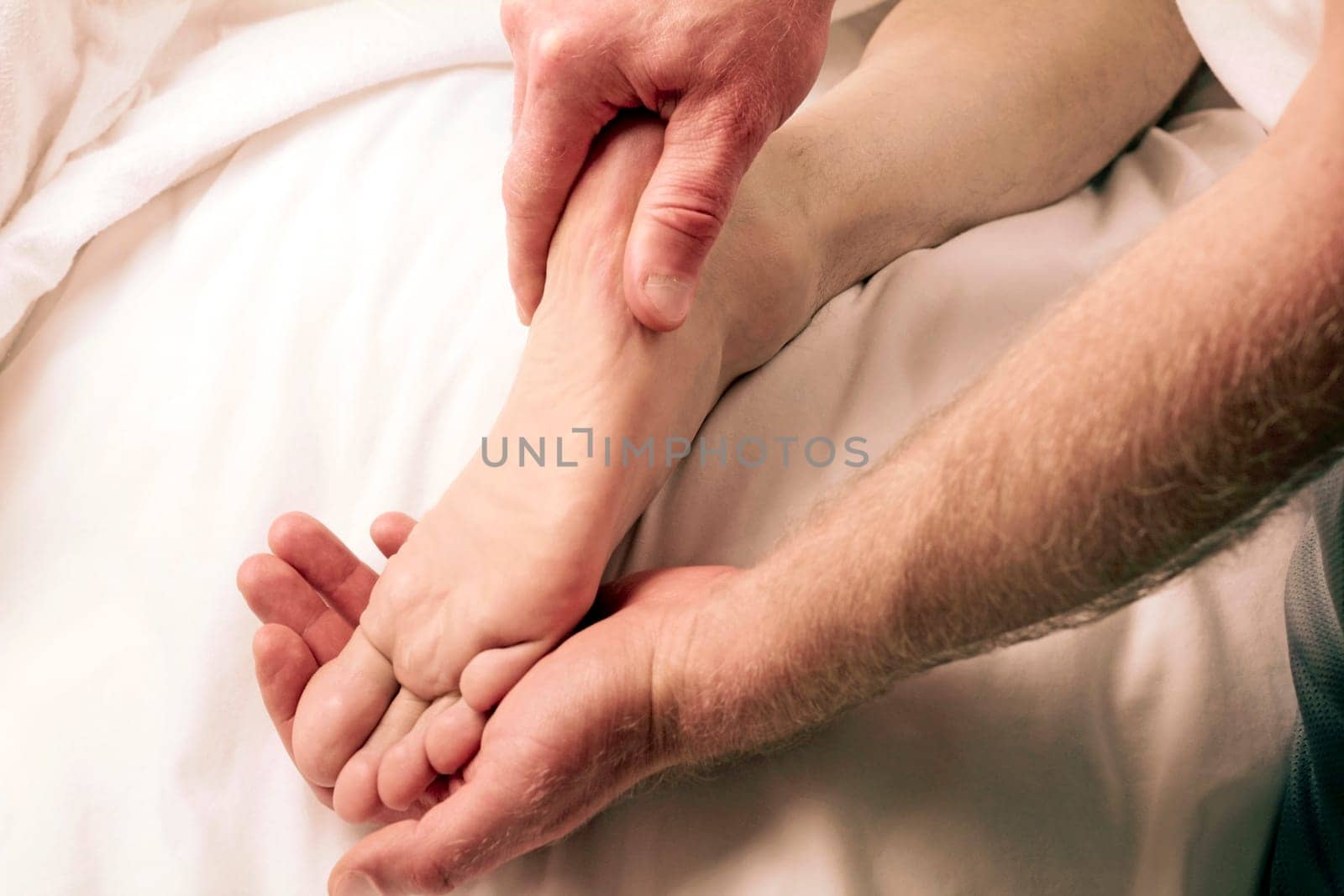 One mature guy receiving and one LMT giving foot massage therapy up close.