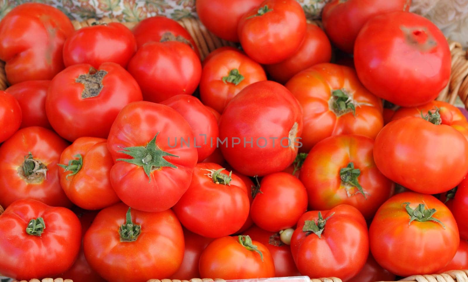 Tomatoes grouped together in a basket at a market.