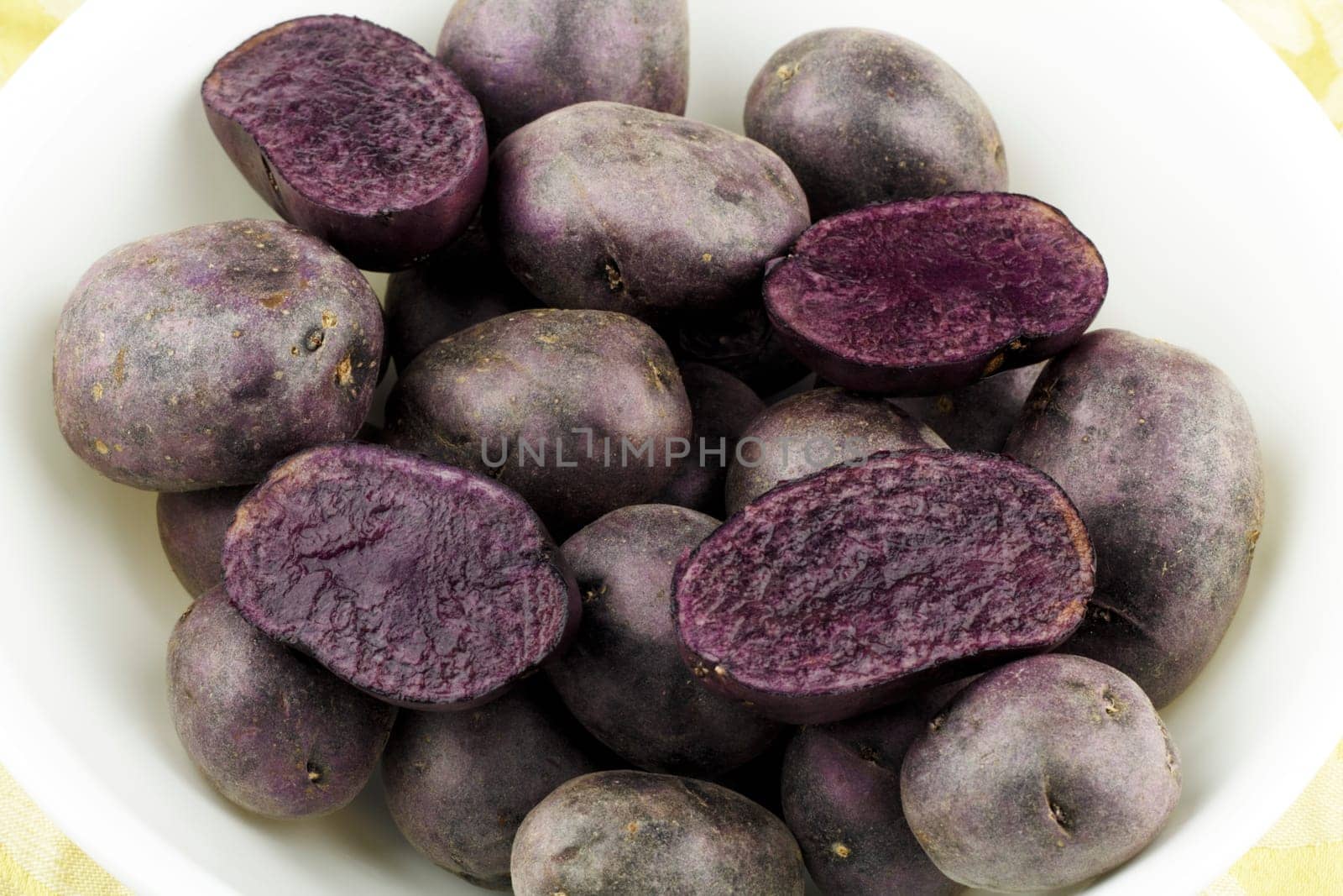 White bowl full of very dark fleshed tuber vegetables.