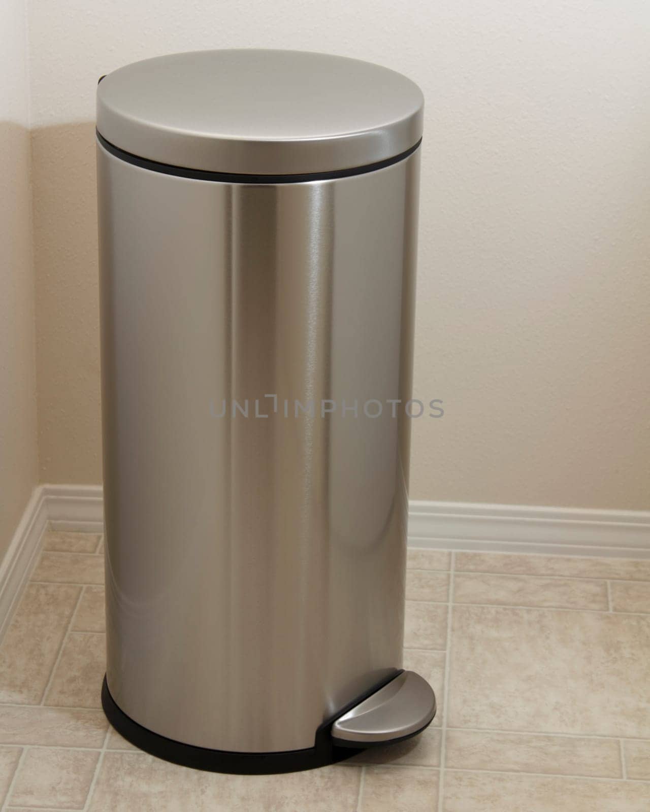 Muted gray metal cylindar with lid opener used for holding dirty clothes or, as closed garbage can.