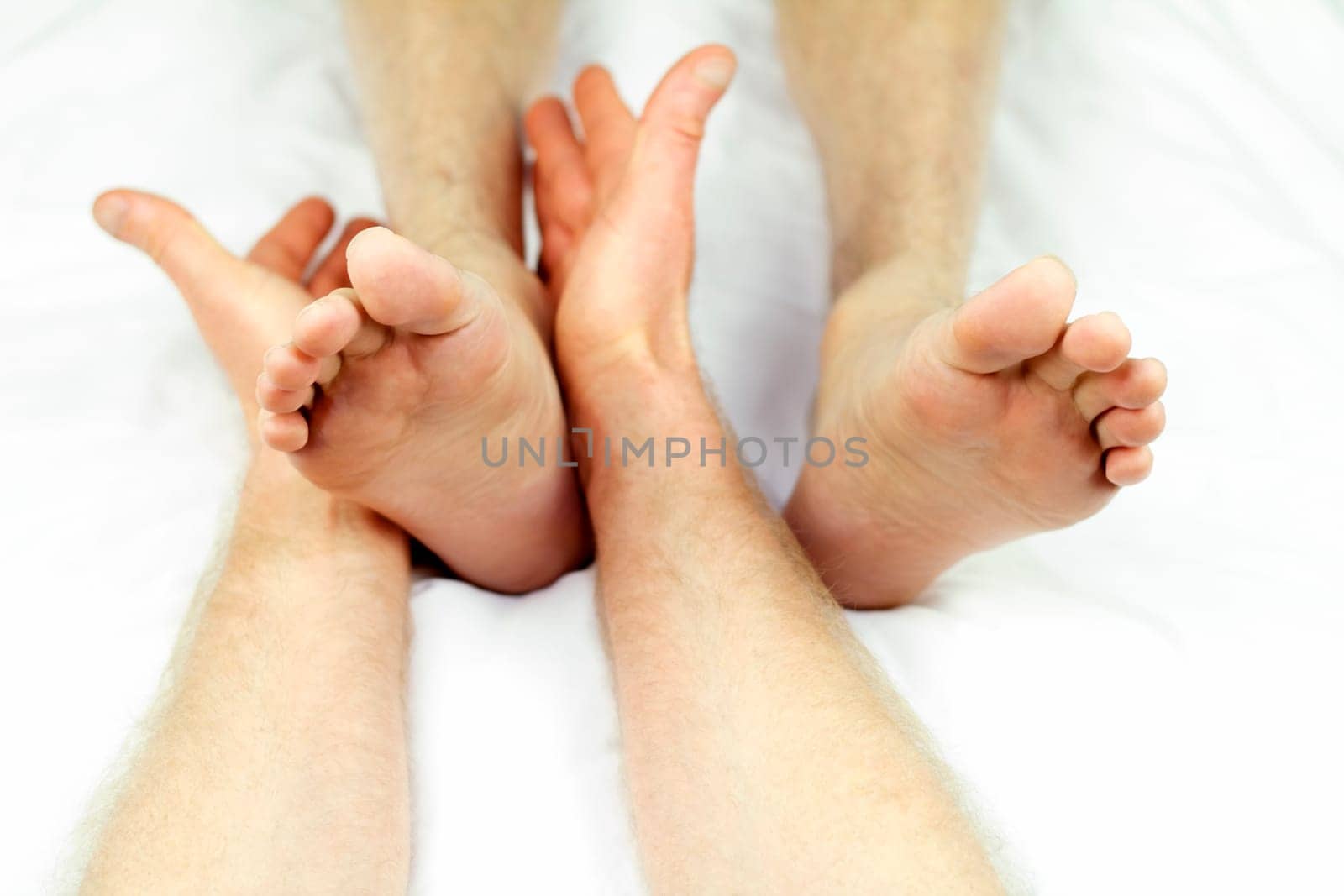 Man getting ankle rolling as part of a reflexology session from a male massage therapist.