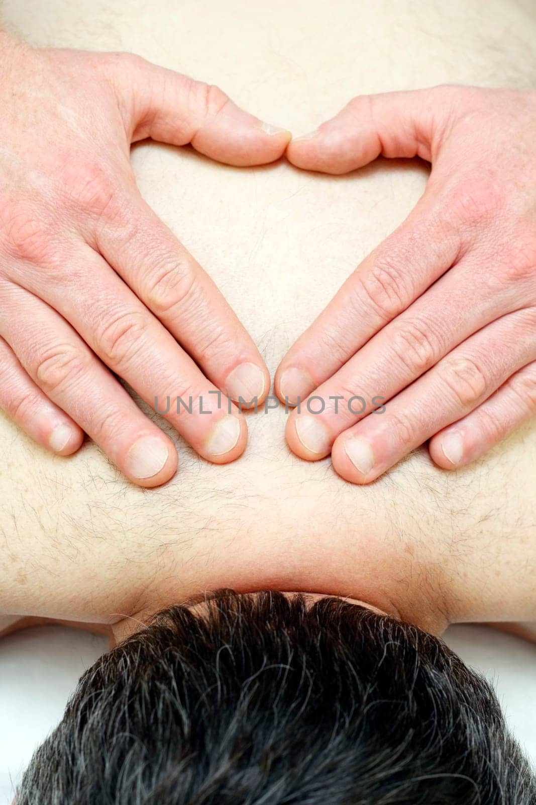 Heart sign made with hands fingers on skin of upper back.