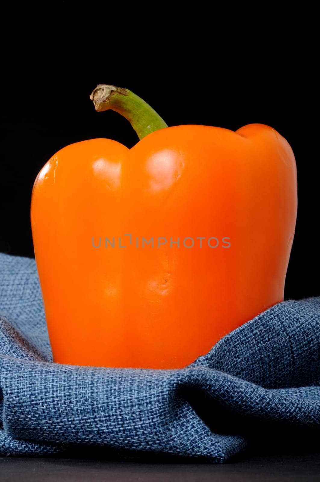 A orange bell pepper isolated over black