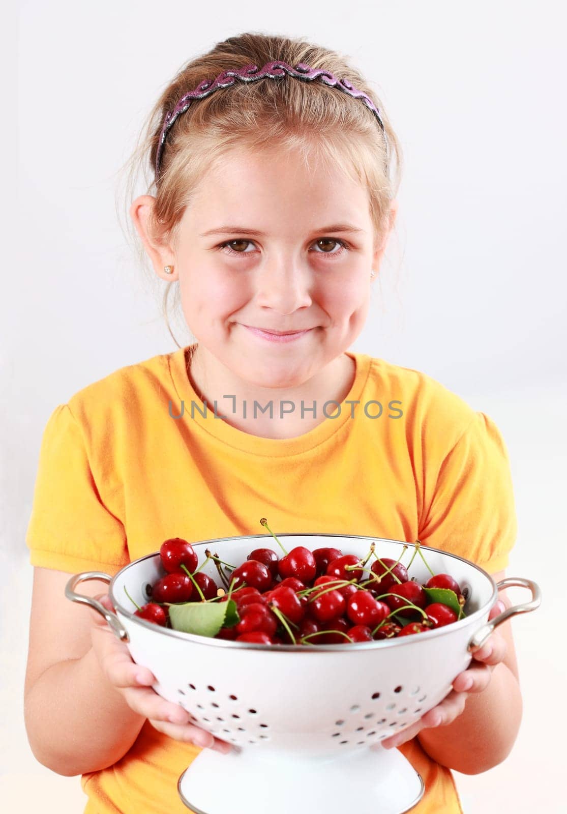 Cute child holding a bowl of fresh cherries