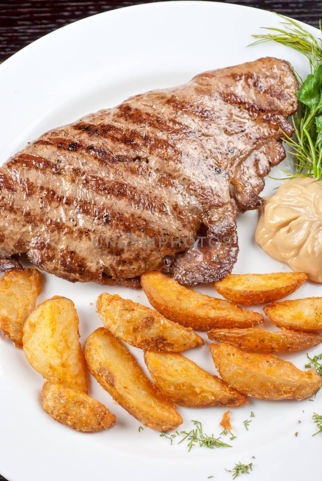 Juicy beef steak stuffed with beef tongue and cheese served with potatoes, greenery and sauce