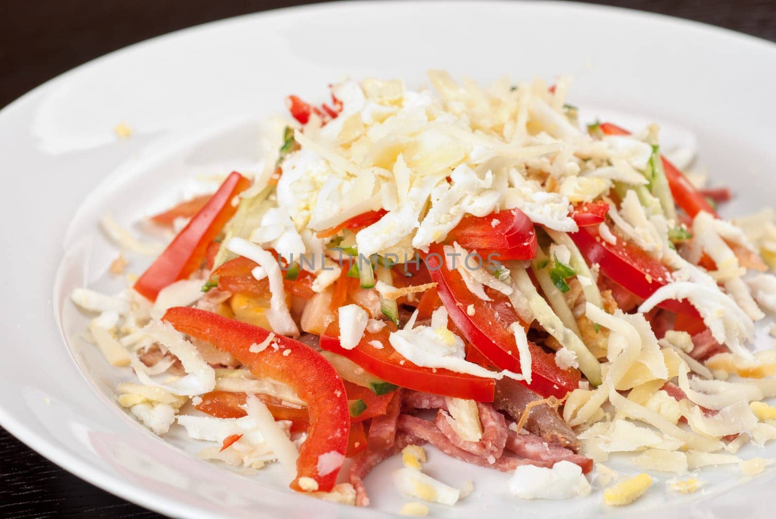 Salad from beef tongue, cervelat, chicken meat, fresh tomatoes, cucumbers, pepper, eggs, cheese and mayonnaise