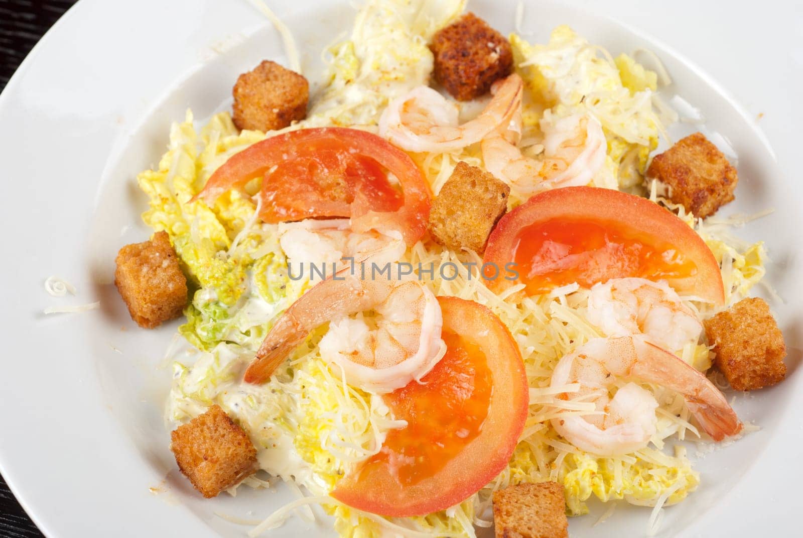 Salad of tiger shrimps, lettuce, chinese cabbage, tomato, garlic rusk, parmesan cheese and sauce