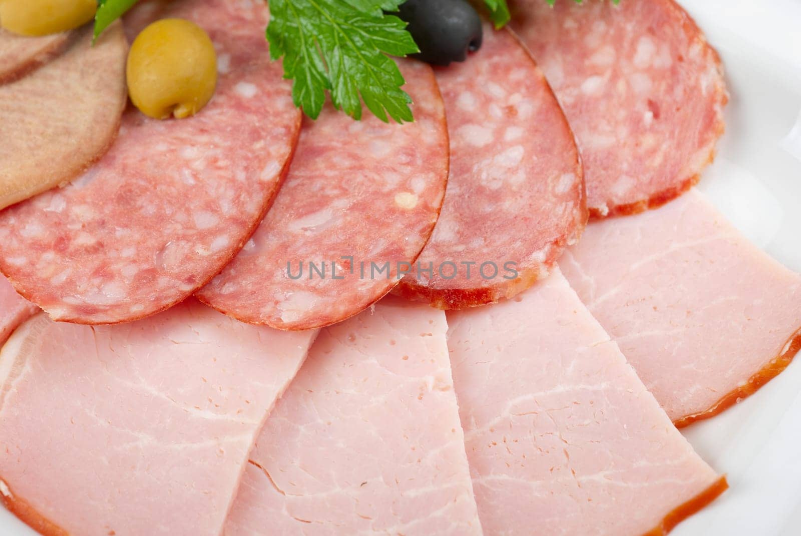 Meat assortment of beef tongue, sausage, meat and ham with greens