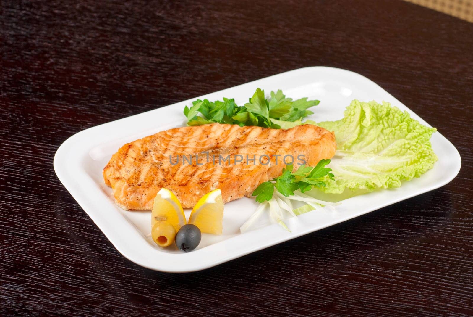 Grilled salmon steak with greens,onion, lemon, lime and olive