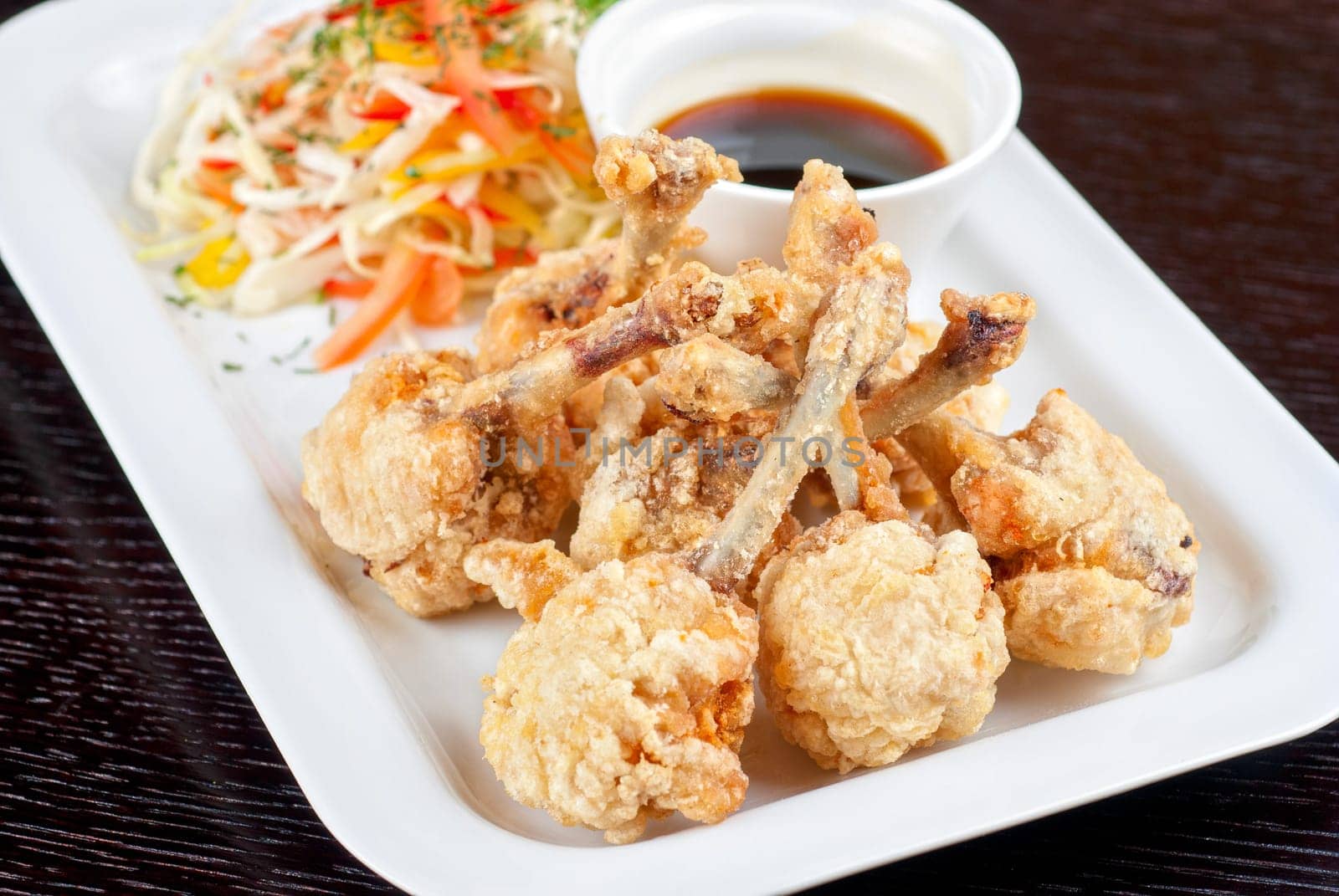 Fried chicken wings garnished with fresh vegetables with Teriyaki sauce