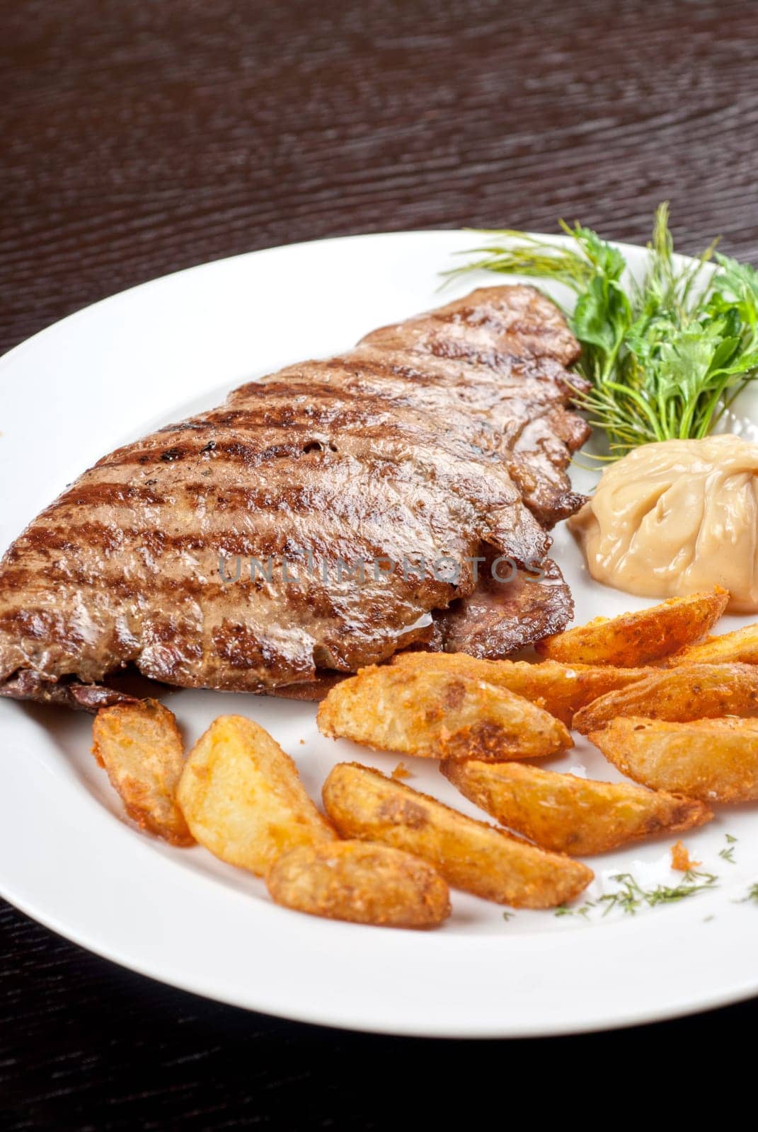 Juicy beef steak stuffed with beef tongue and cheese served with potatoes, greenery and sauce