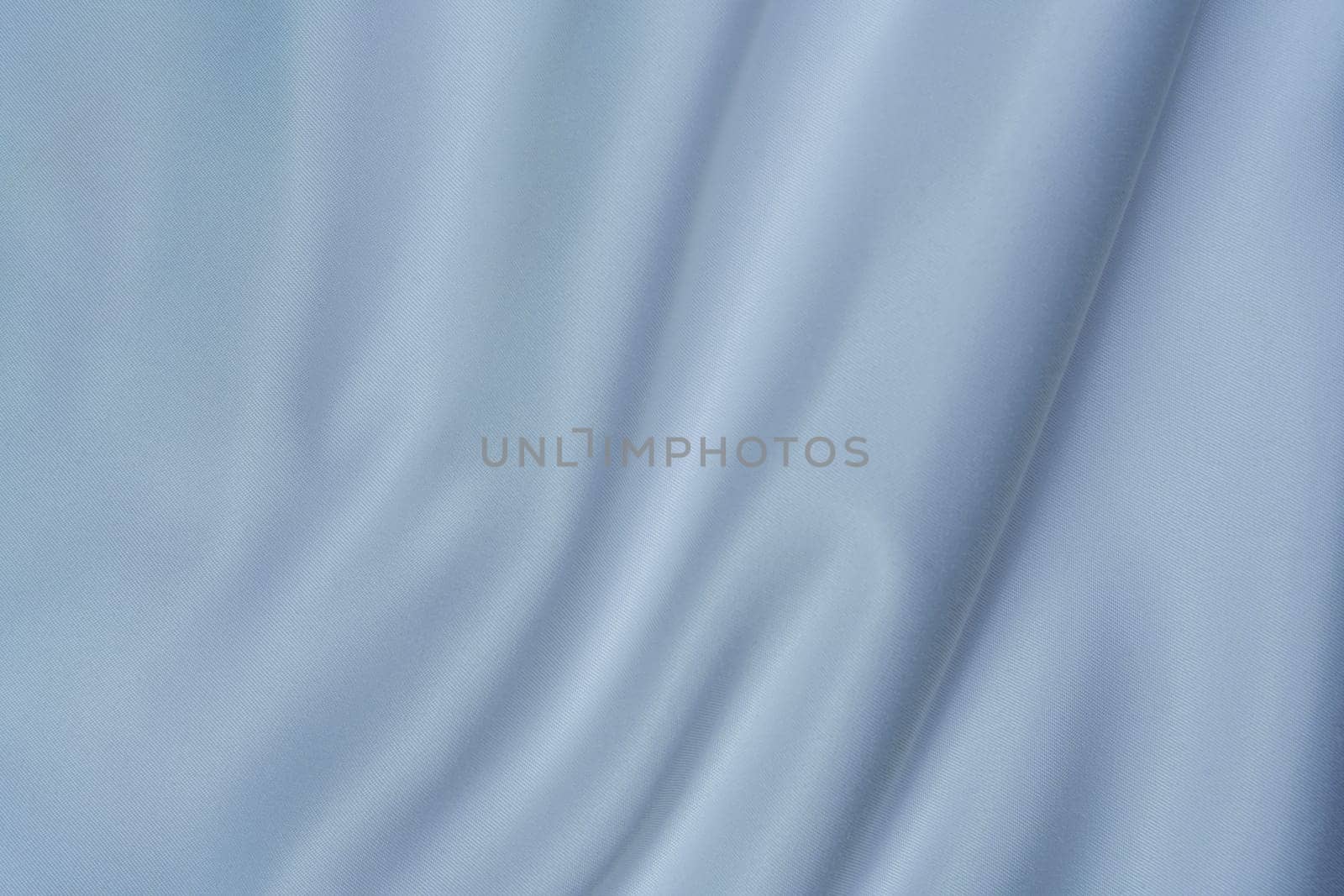 Close-up of soft white fabric with gentle folds creating a swirl pattern, perfect for backgrounds, textures, and design projects.