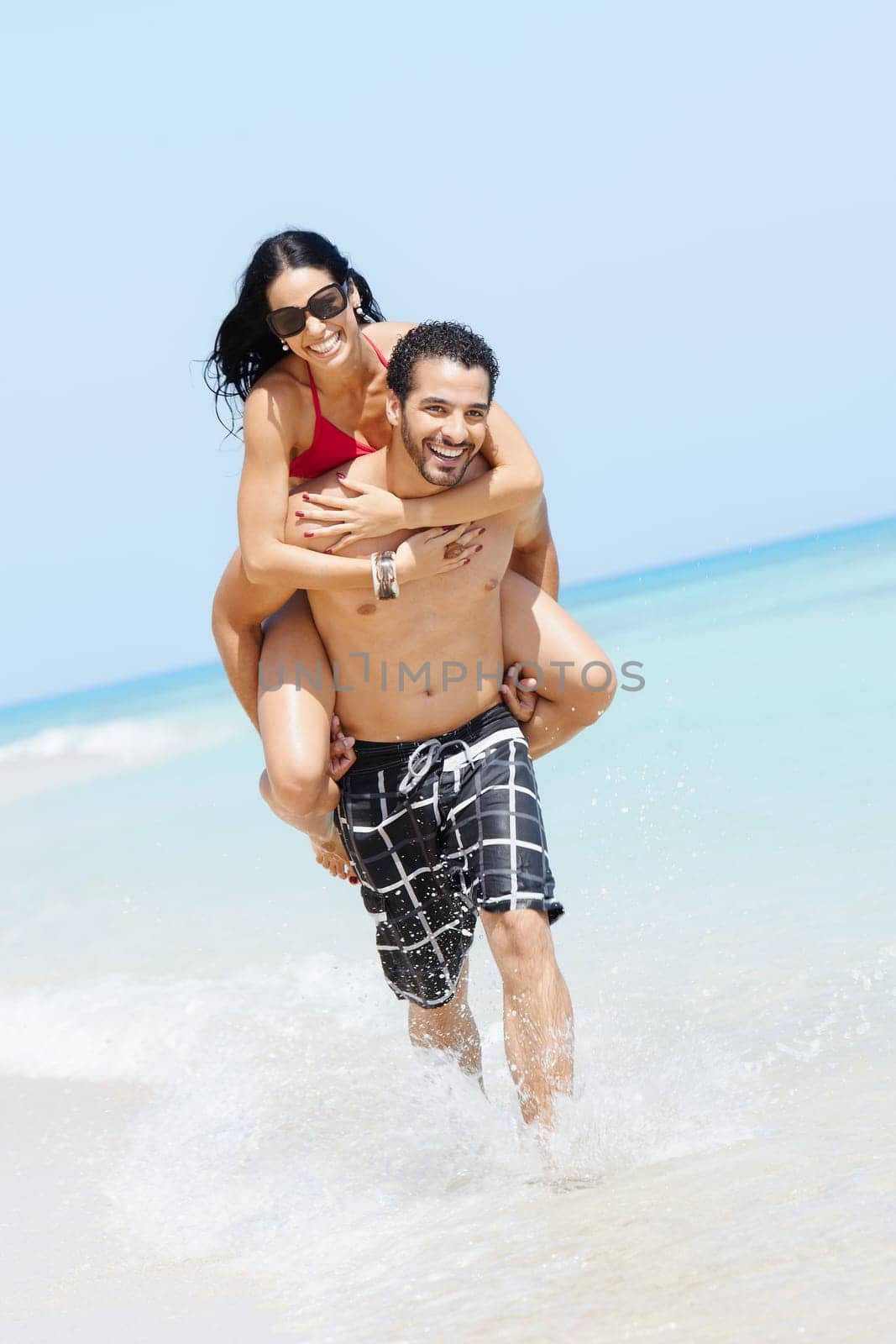happy maried adult couple having fun and playing on the sea shore in cuba. Vertical shape, full length, copy space
