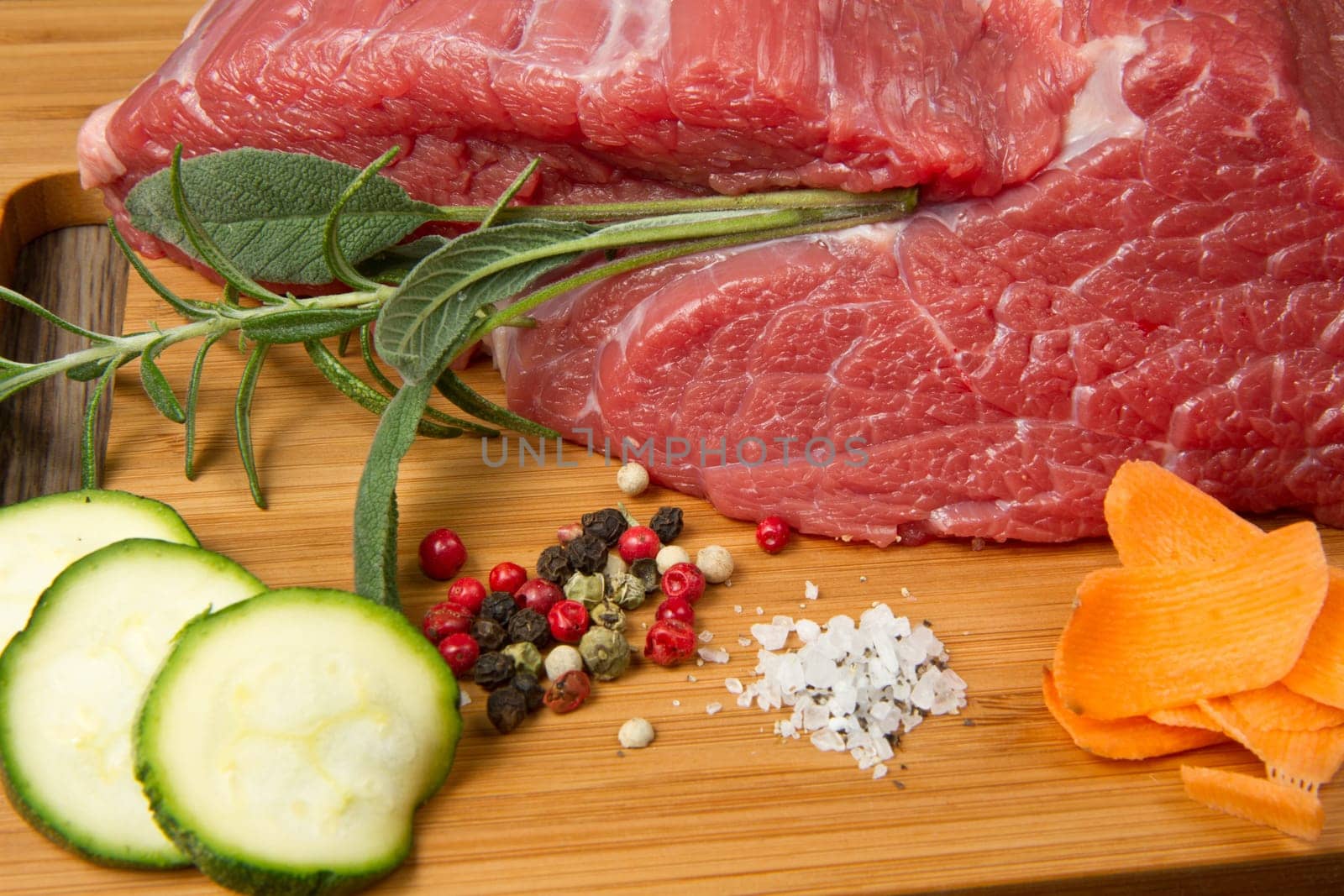 red meat with pepper and rosemary on wooden board
