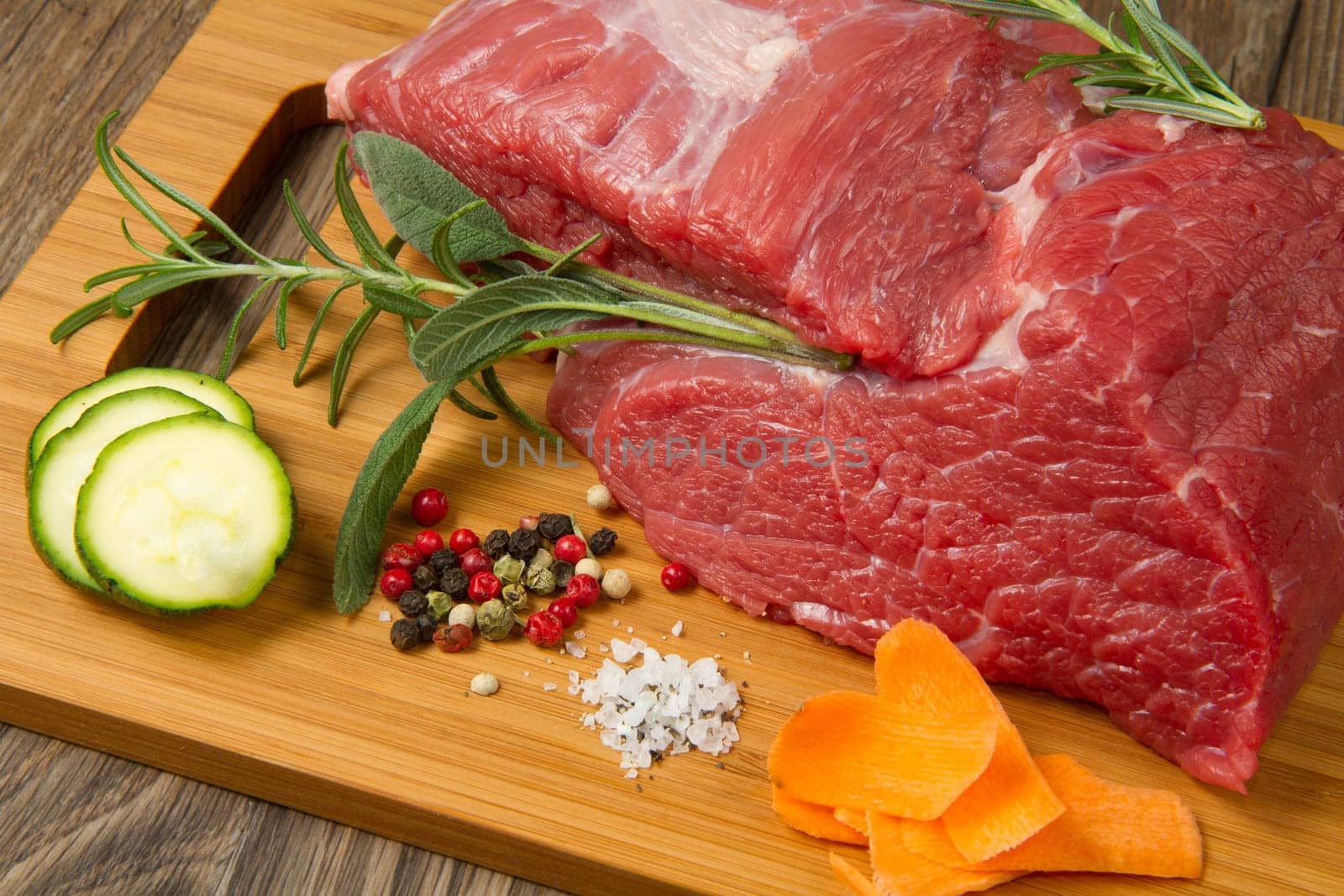 red meat with pepper and rosemary on wooden board