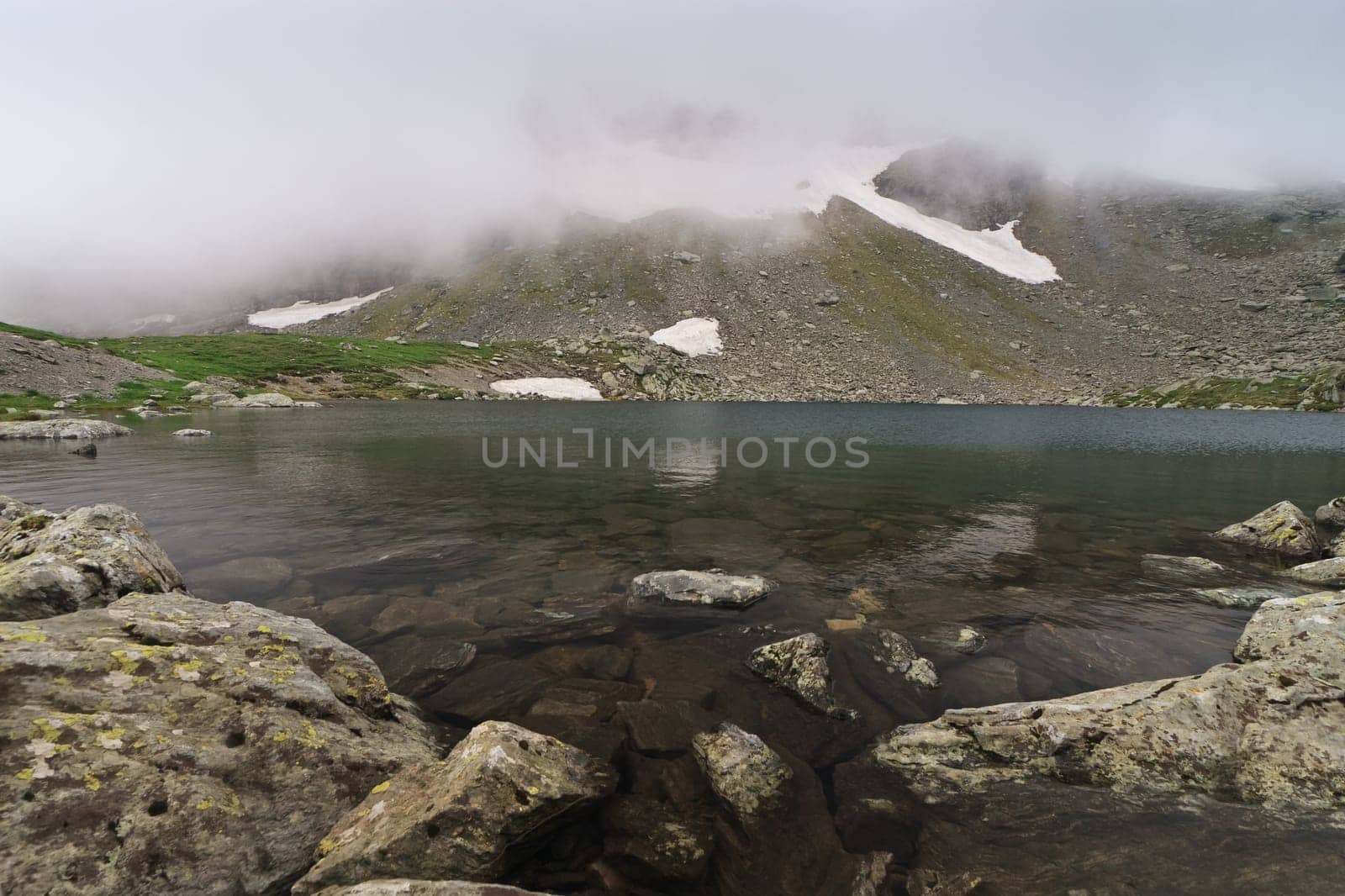 snow and fog near a mountain lake