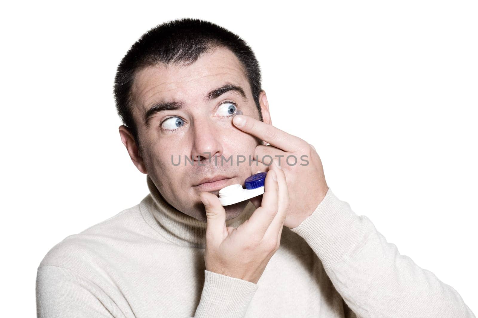 Portrait of a handsome expressive man putting contact lenses in studio on white isolated background