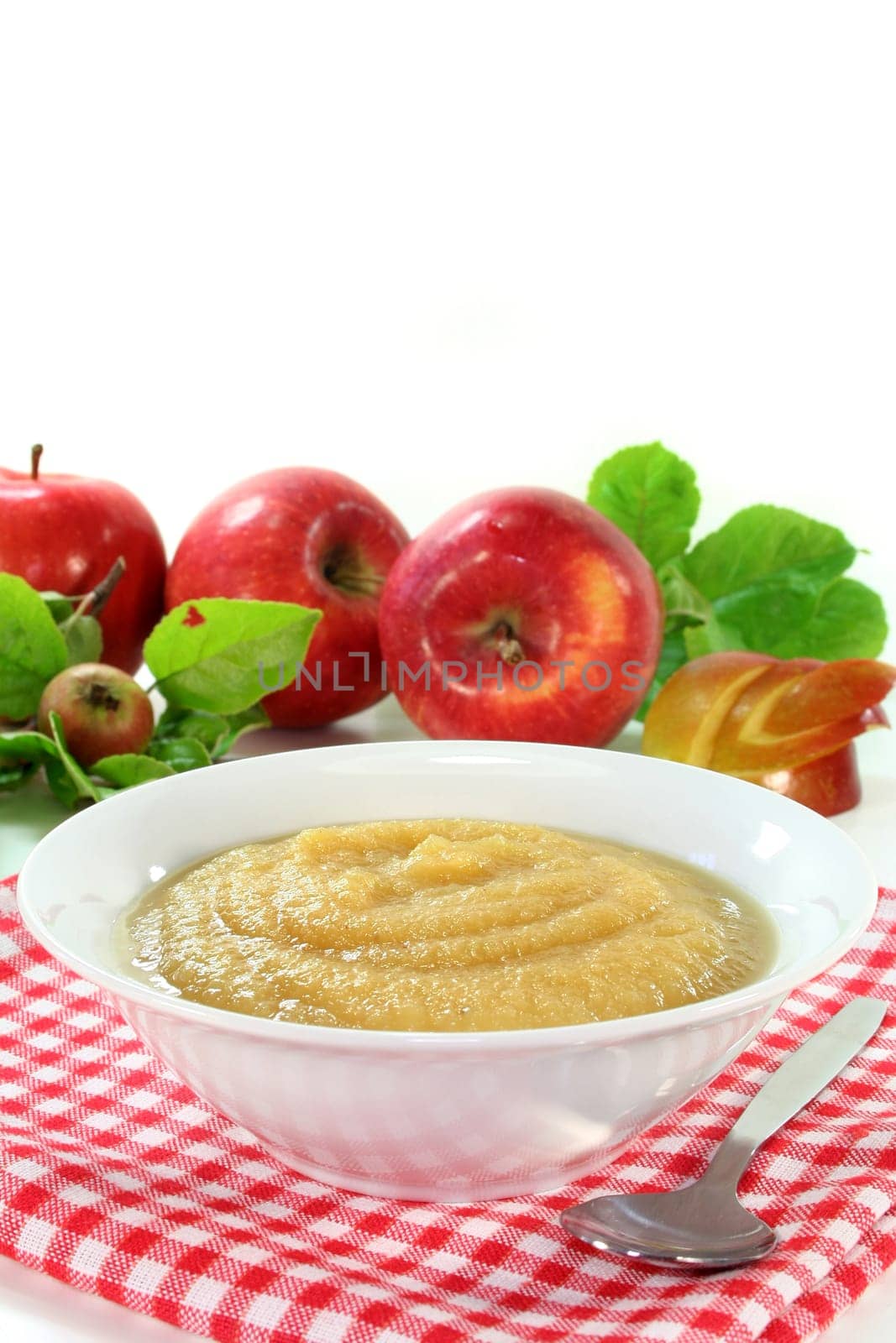a white bowl with applesauce and fresh apples