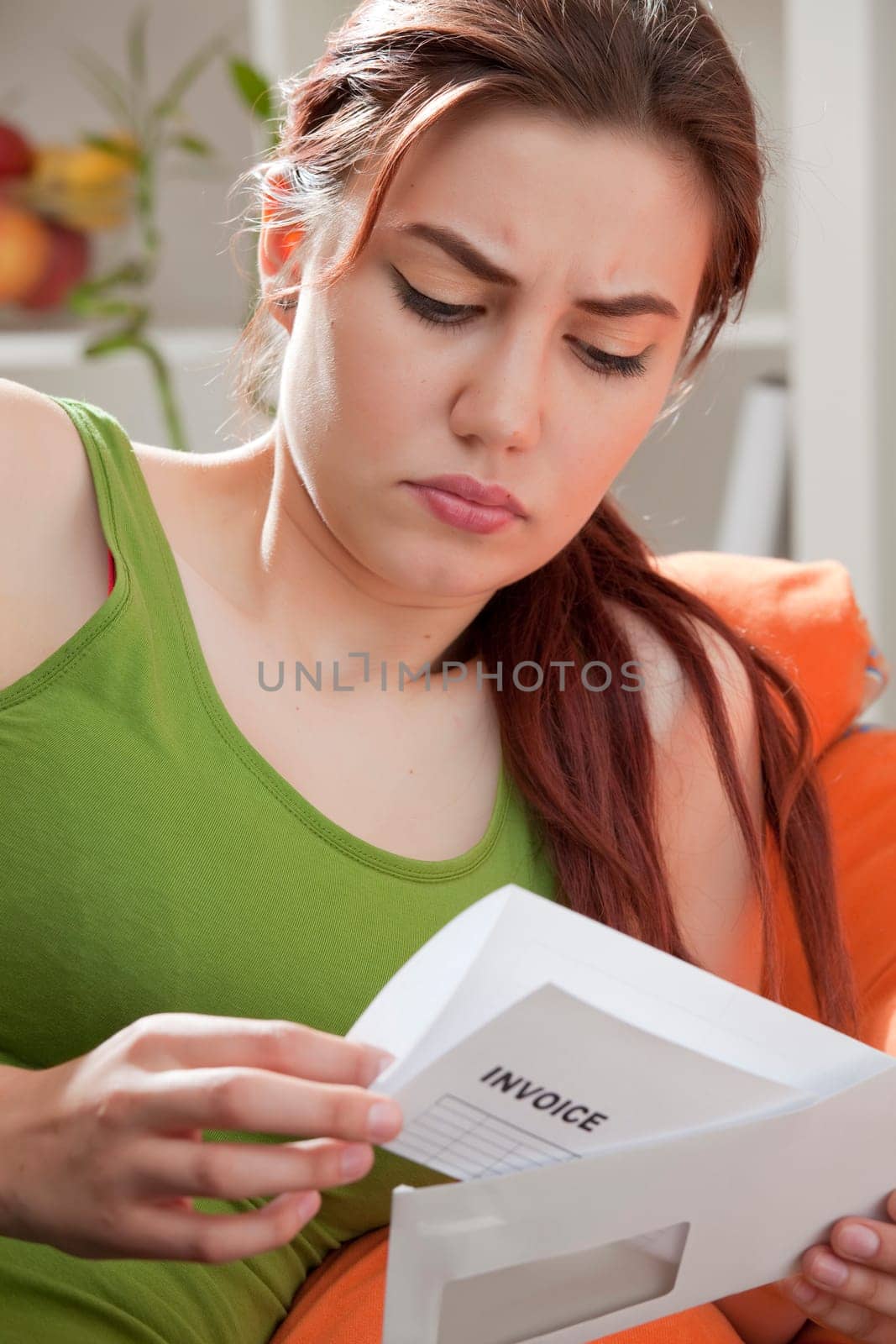 young woman holding envelope and reading invoice