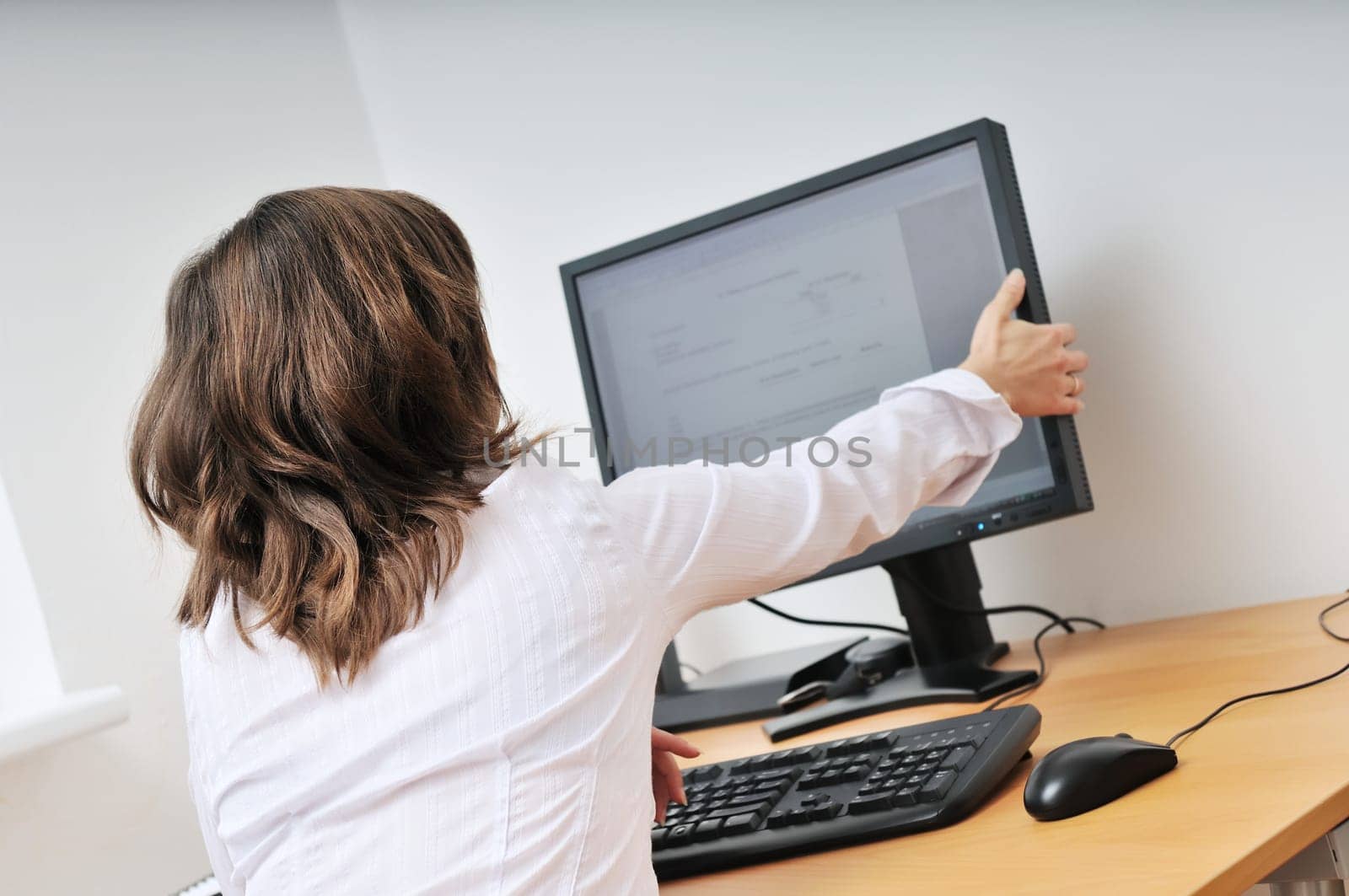 Business person (young woman) adjusting computer monitor - office interior