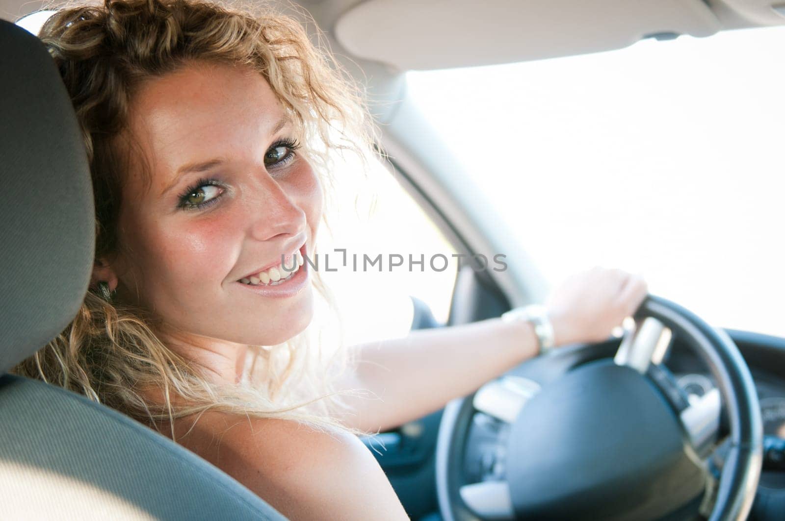 Portrait of young smiling woman inside a car