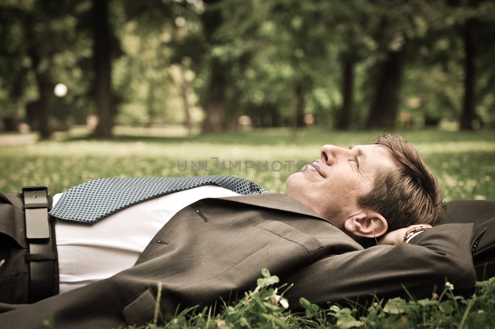 Senior people series - mature business man lying on grass and relaxing in park