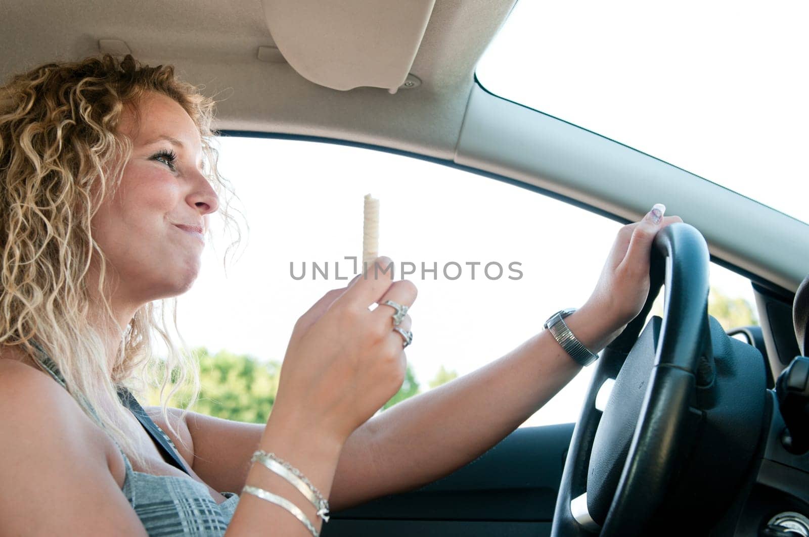 Young woman eating sweets while driving car