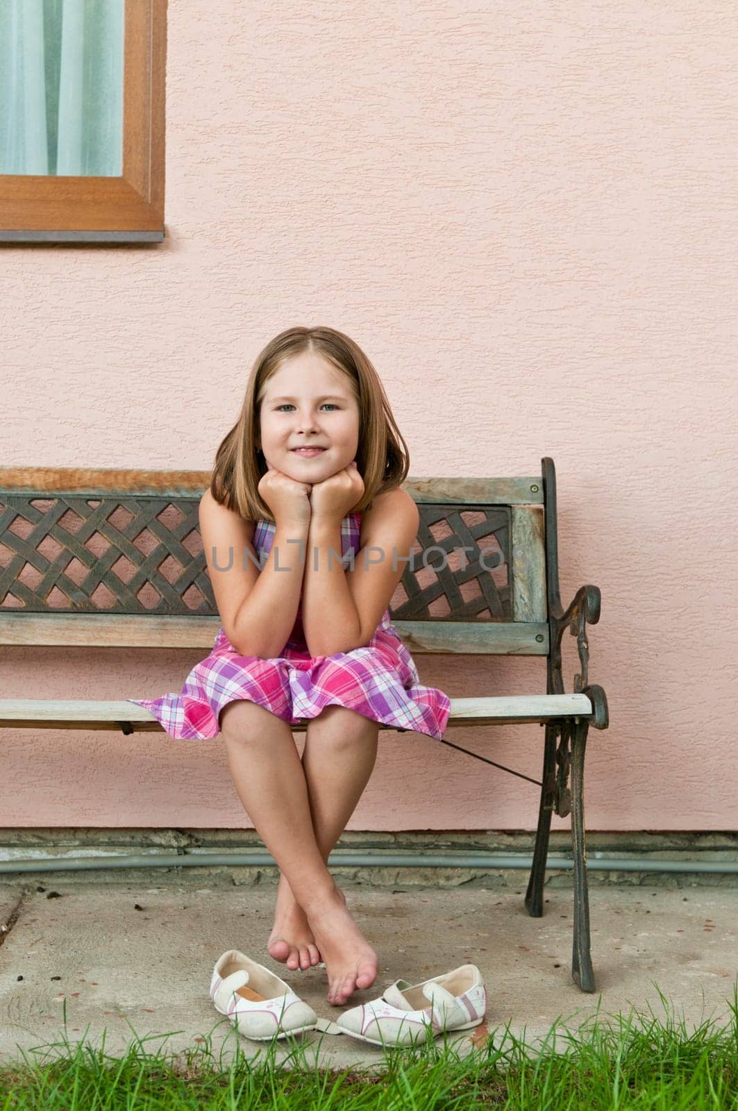 Portrait of cute smiling child sitting on bench - wall in background