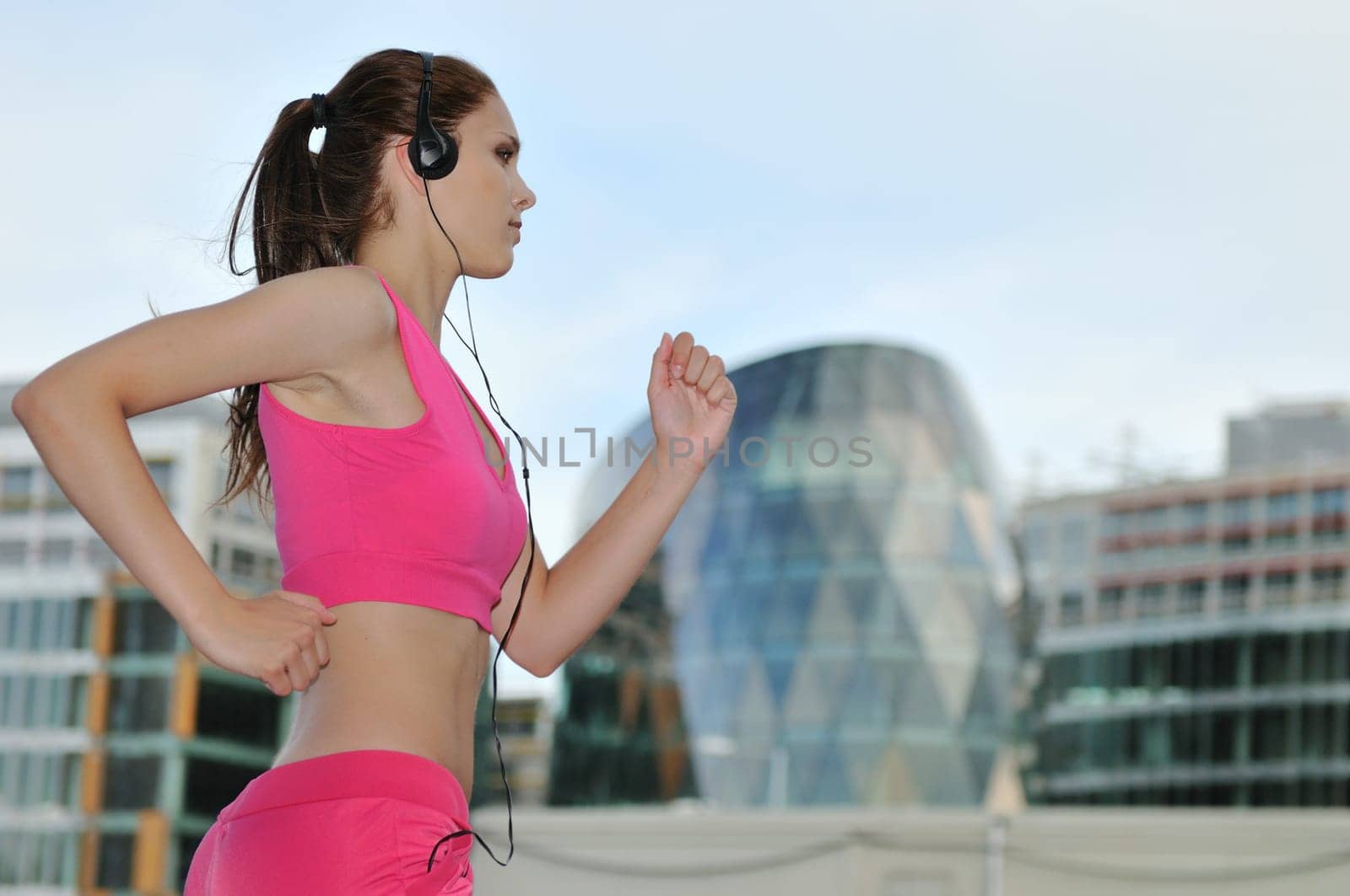 Person (young beautiful woman) listening music running (jogging) in city street