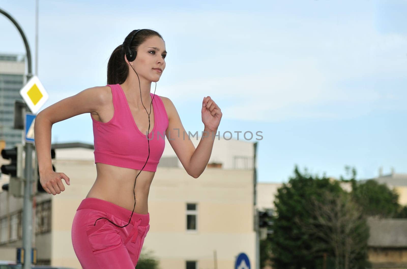 Person (young beautiful woman) listening music running (jogging) in city street