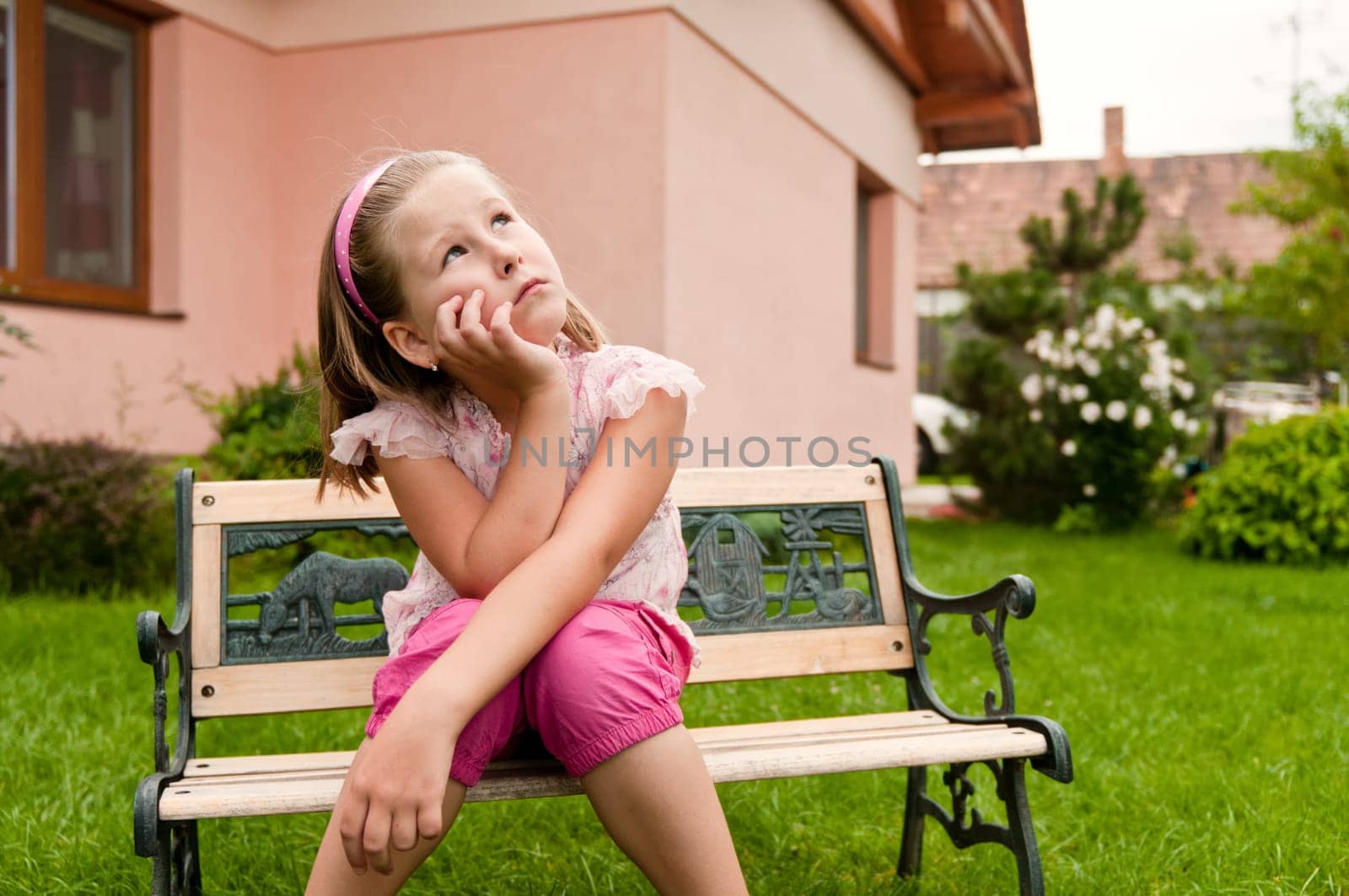 Girl having big problems - sitting on bench in backyard with family house behind