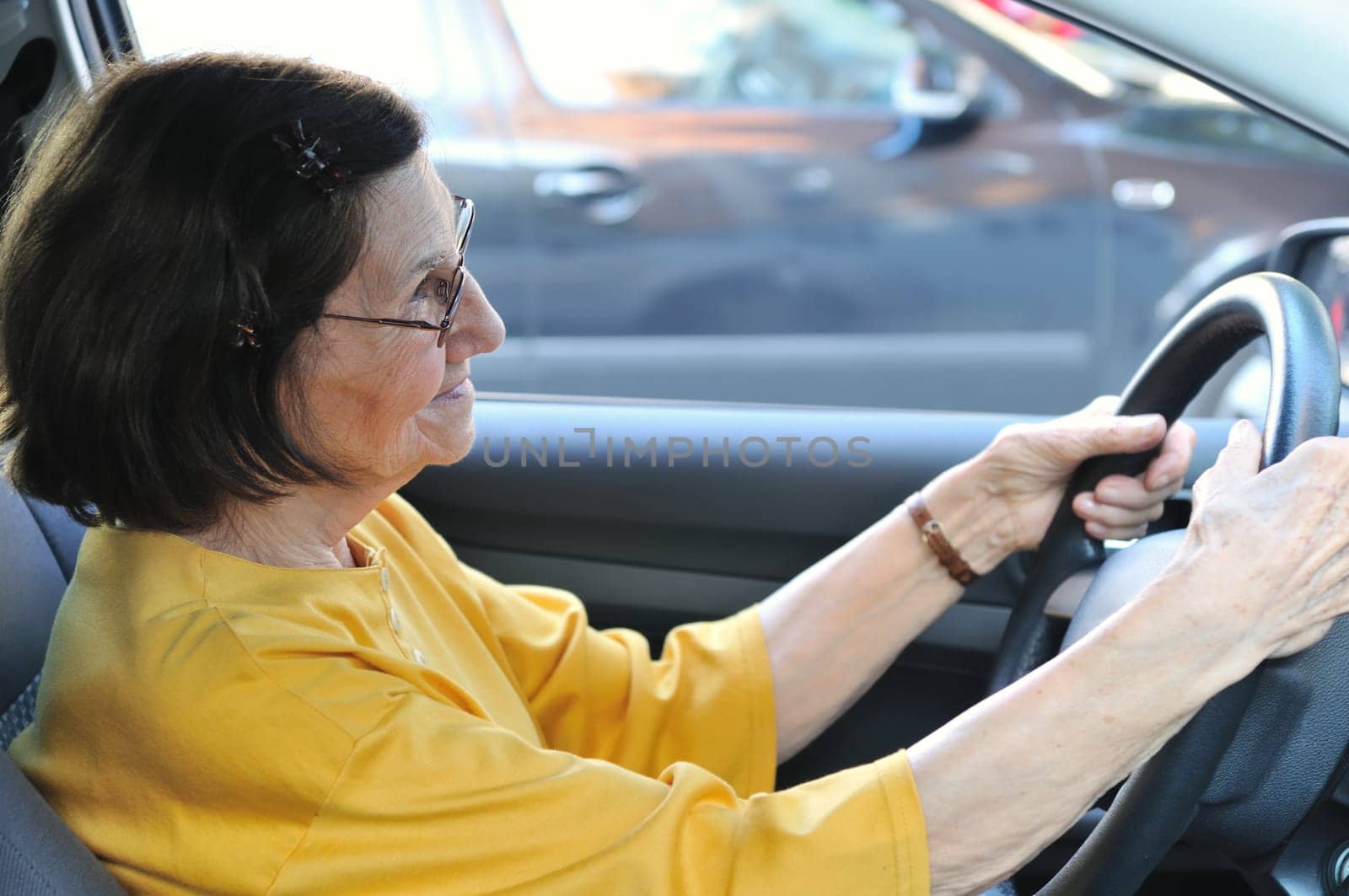 Active senior woman - grandmother driving car, detail