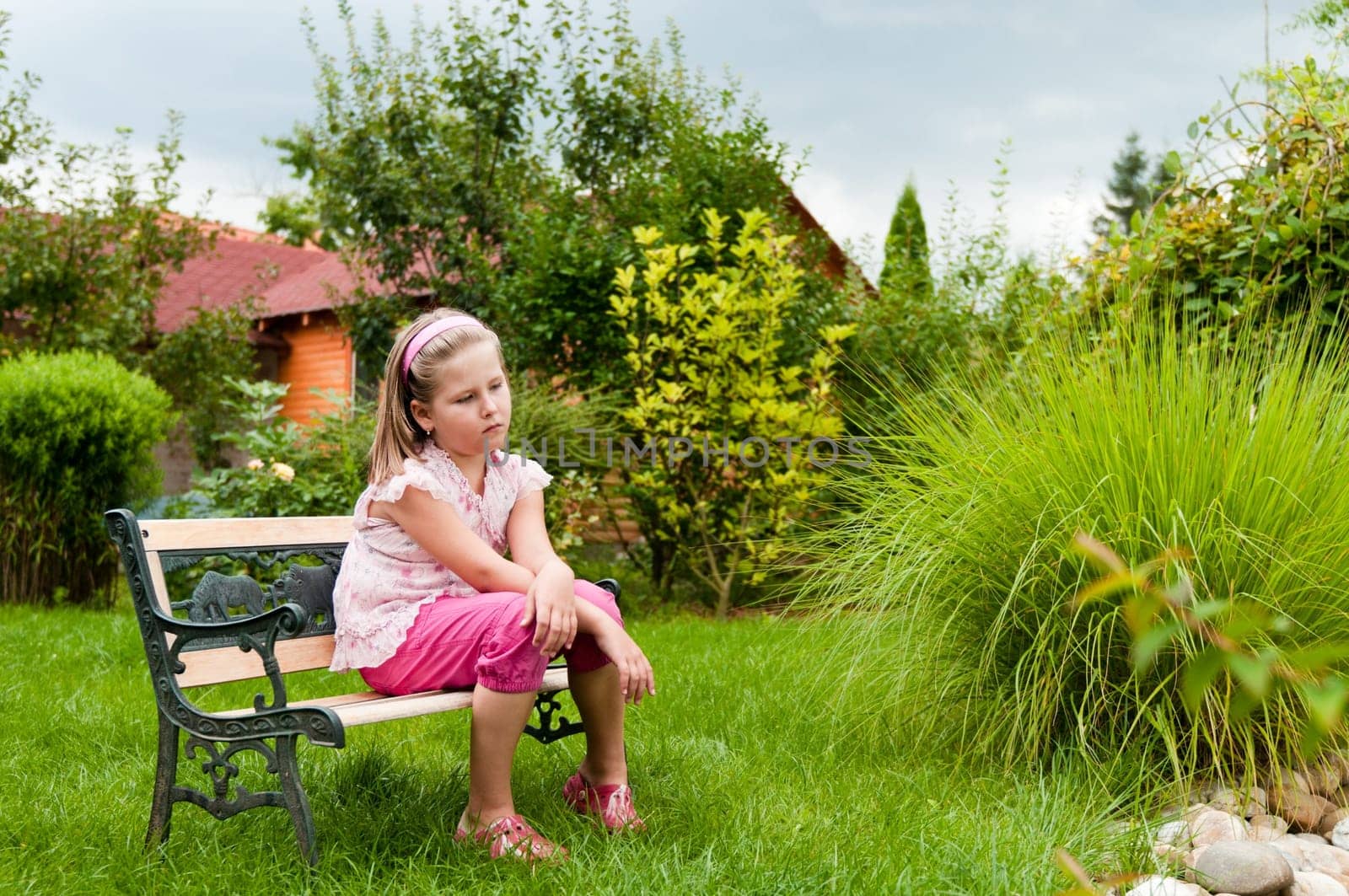 Girl having big problems - sitting on bench in backyard with family house behind