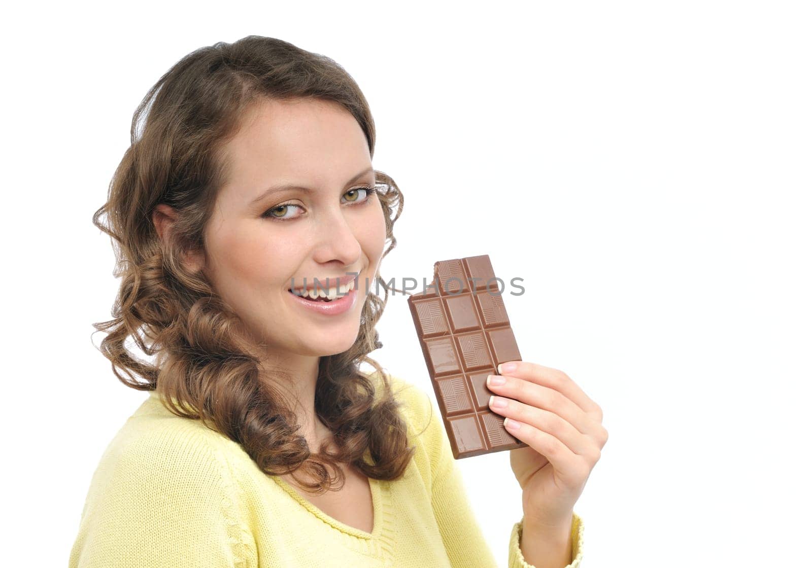 Young smiling woman in yellow eating milk chocolate isolated on white background