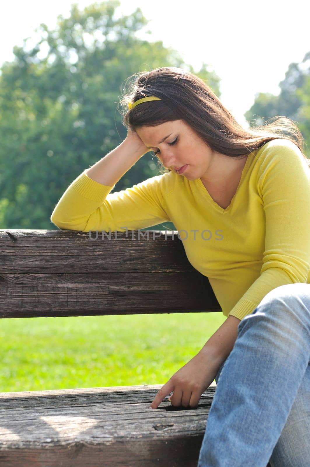 Portrait of worried teenager siting on bench in park