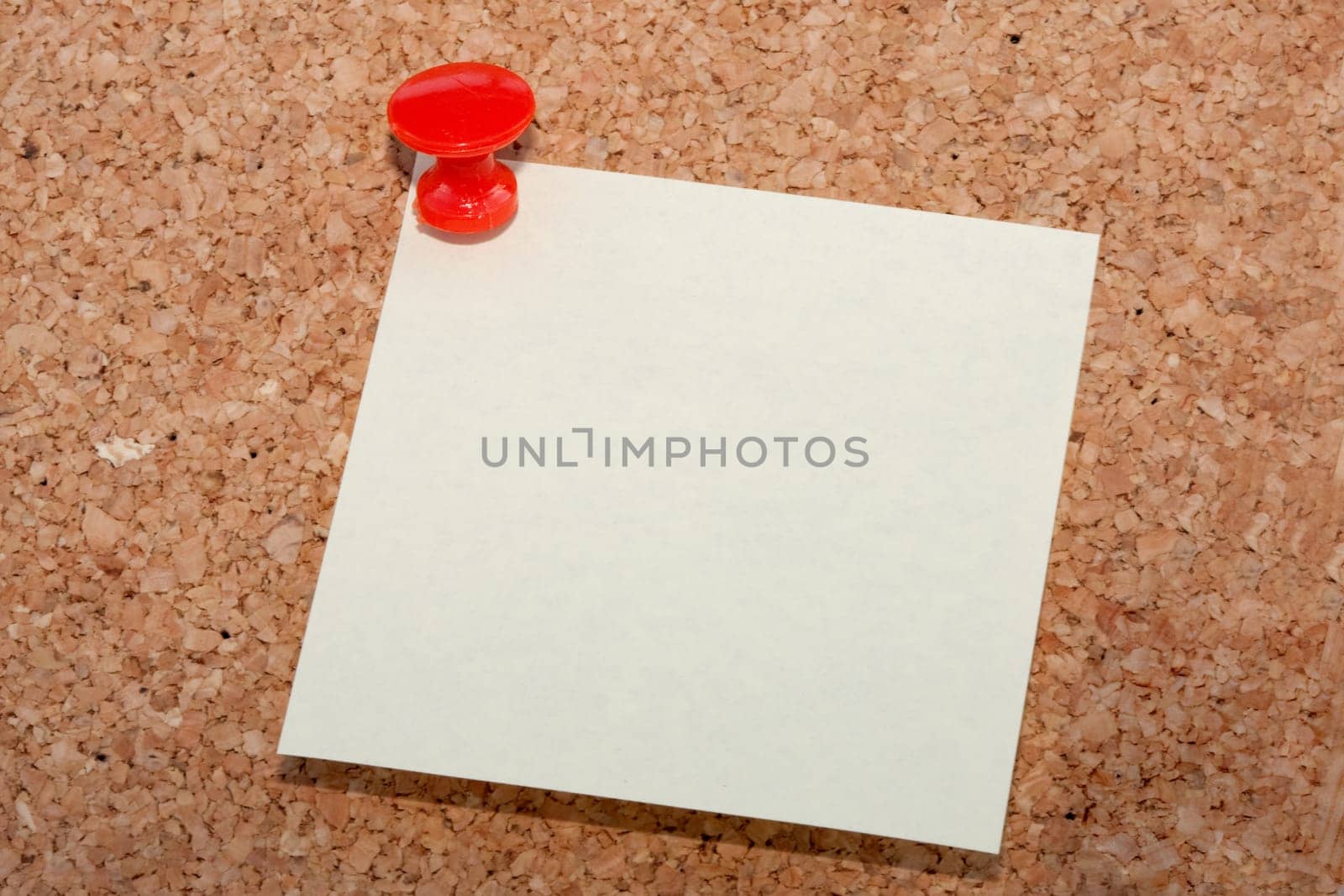 Red pin with note pinned to cork noticeboard
