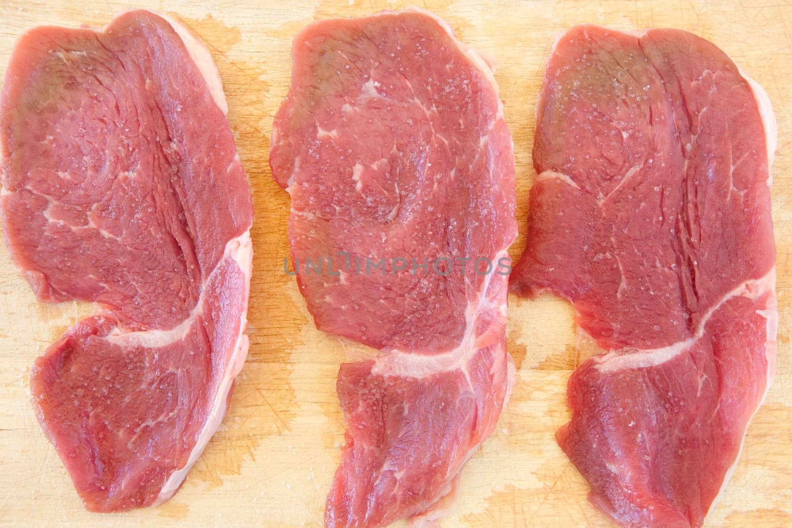 Three steaks raw salted pork on cutting board