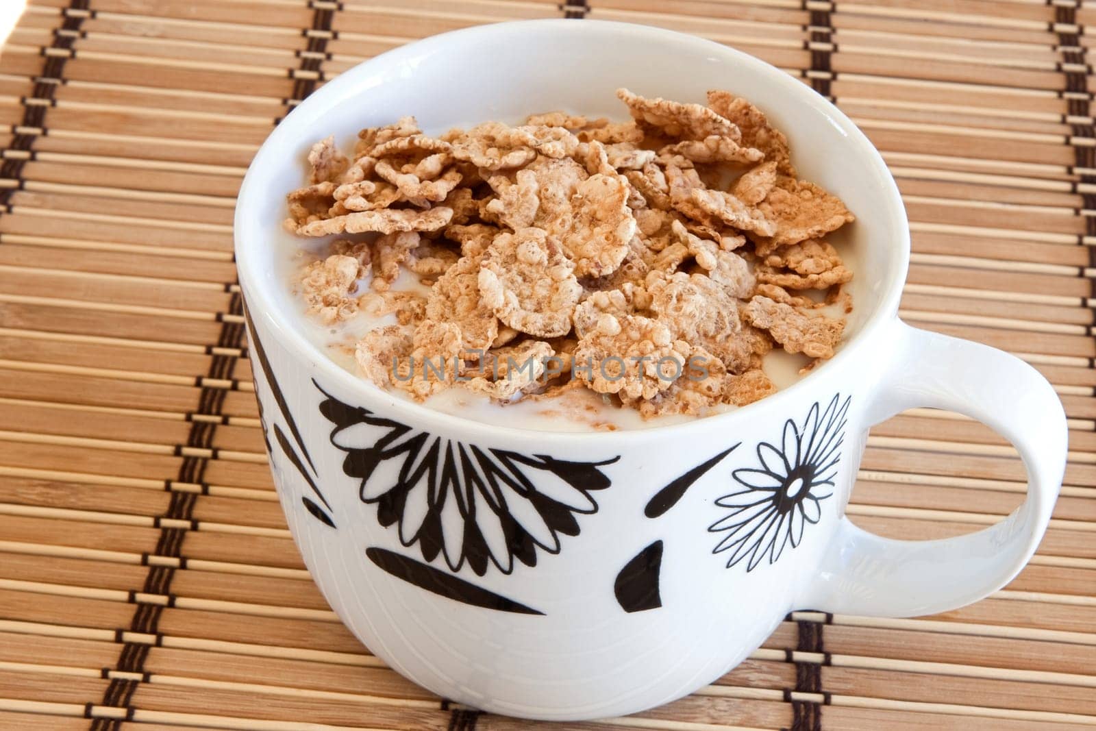 Breakfast bowl of cereal and milk on bamboo tablecloth