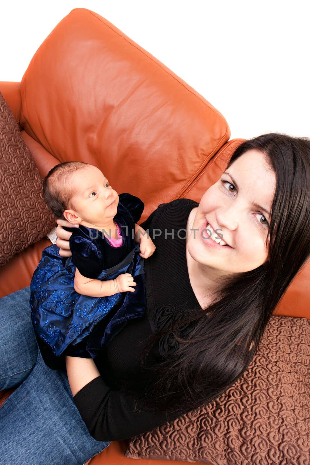 A newborn baby being held in the arms of her mother while seated on the sofa.