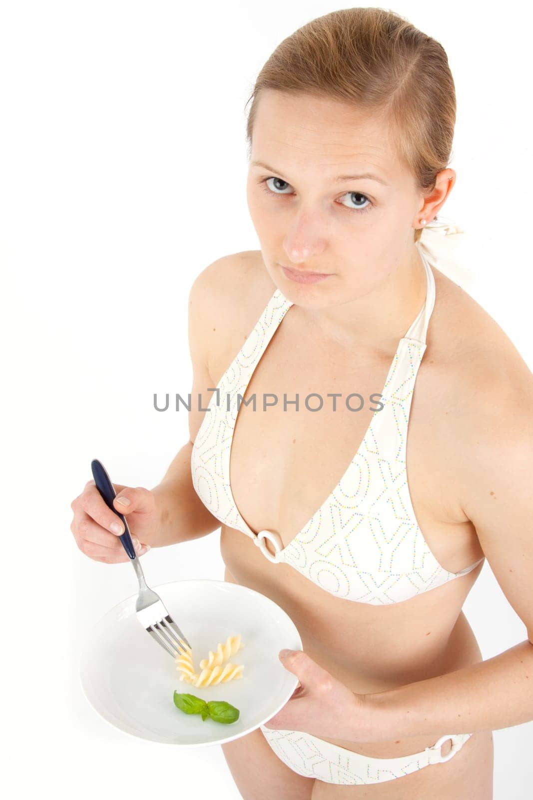 Young woman in bikini eating noodles from a small plate