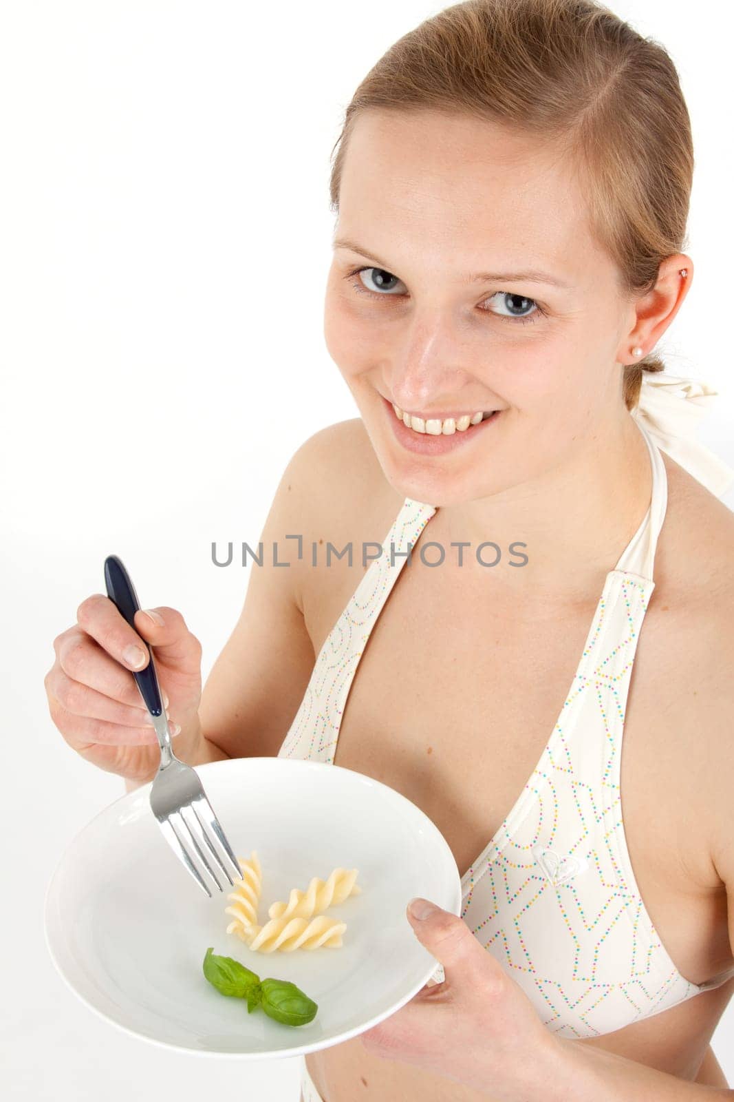 Young woman in bikini eating noodles from a small plate