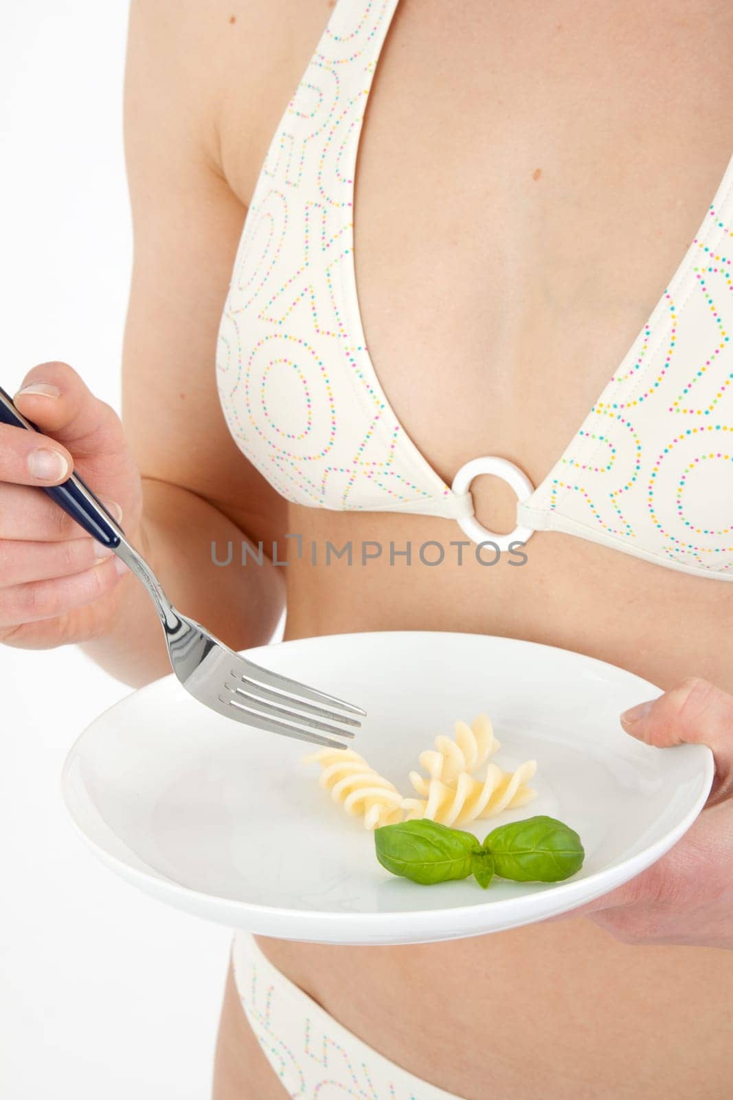 Young woman in bikini eating noodles from a small plate