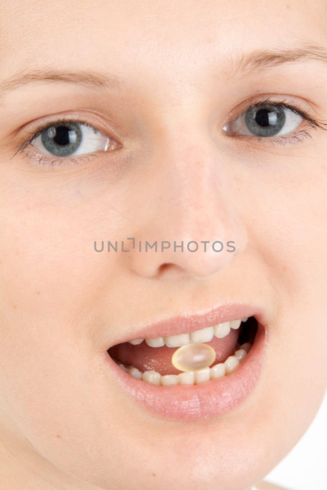 Young woman with a pill between her teeth