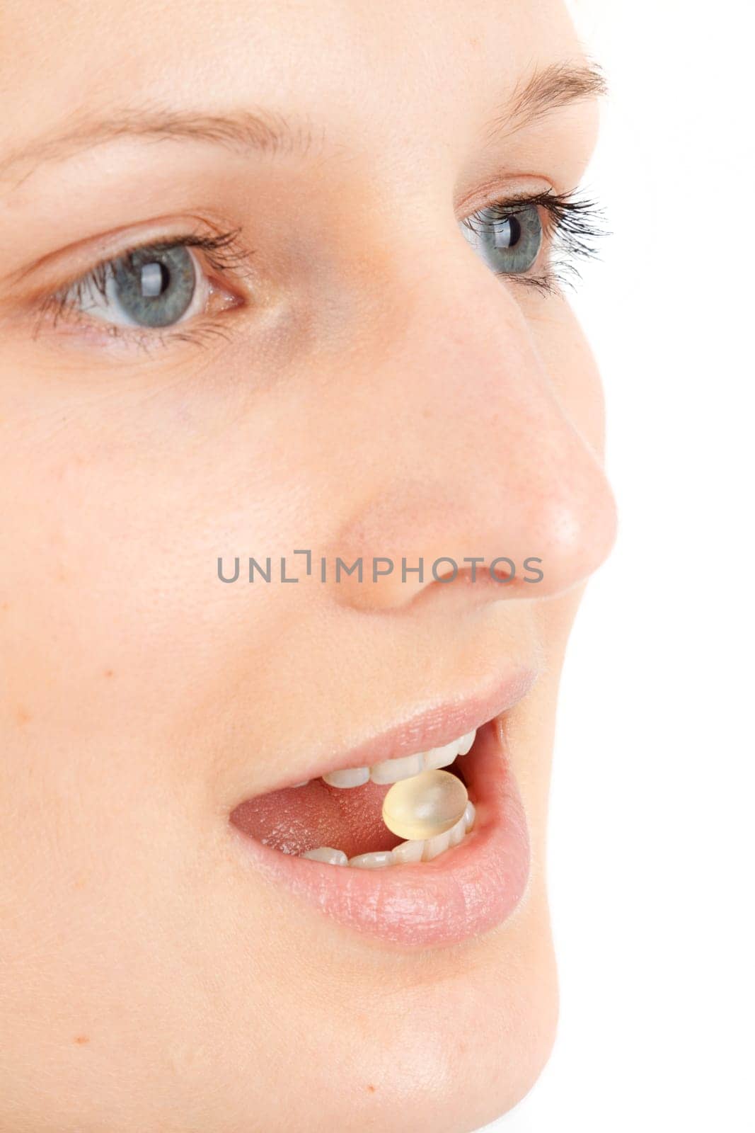 Young woman with a pill between her teeth
